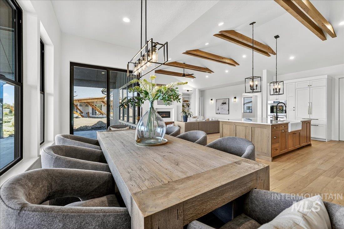 Dining area featuring light wood-style flooring, a lit fireplace, recessed lighting, and a chandelier