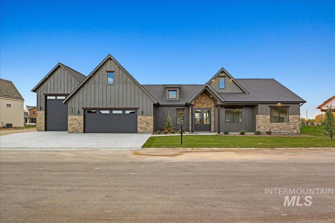 View of front of home with stone siding, board and batten siding, driveway, and a front yard