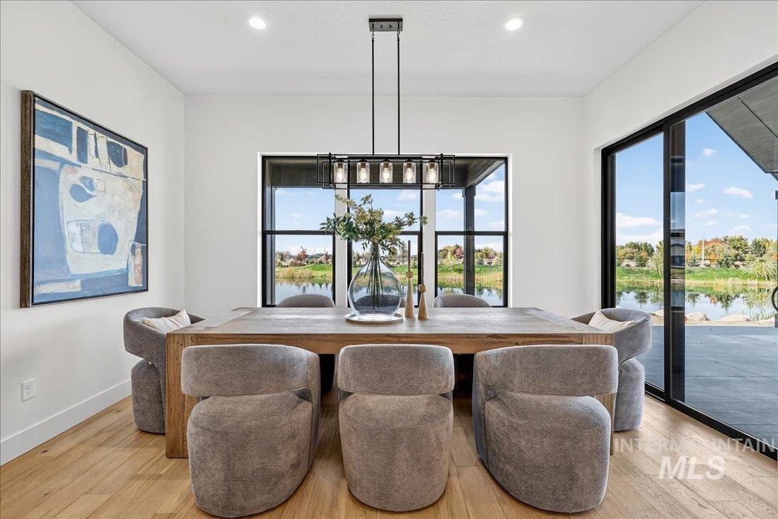 Dining room with a water view, light wood-type flooring, and recessed lighting