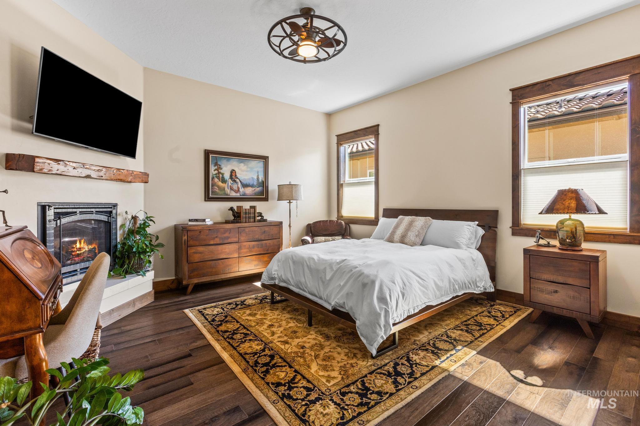 Bedroom with a warm lit fireplace and dark wood-type flooring