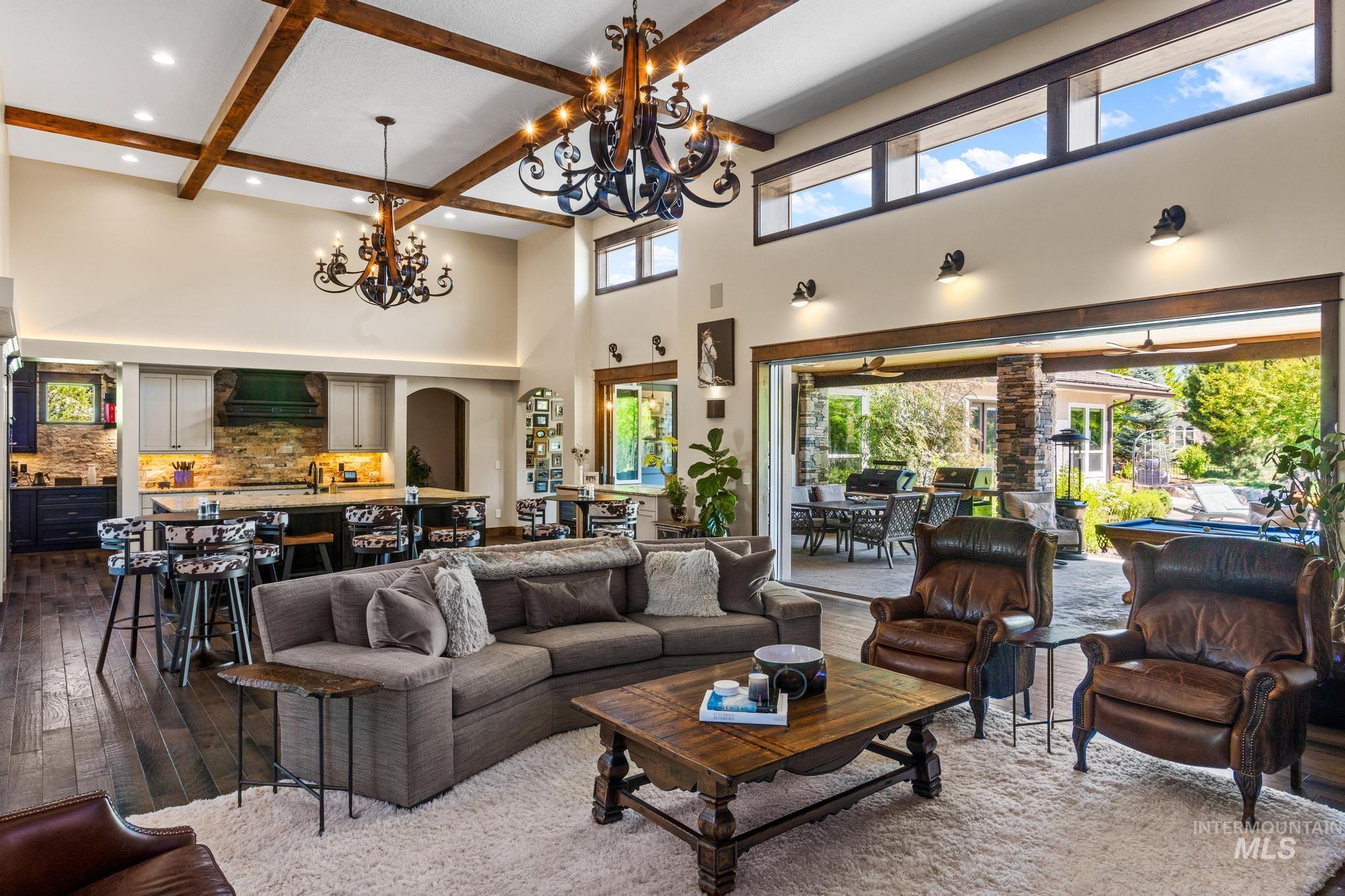Living area with a high ceiling, dark wood-style floors, beamed ceiling, a chandelier, and recessed lighting