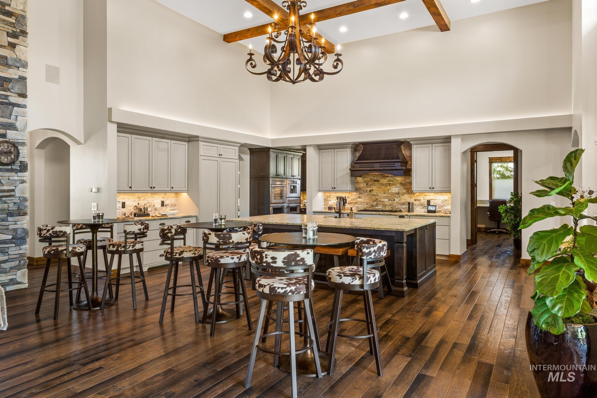Dining room with a towering ceiling, dark wood finished floors, arched walkways, beamed ceiling, and a chandelier