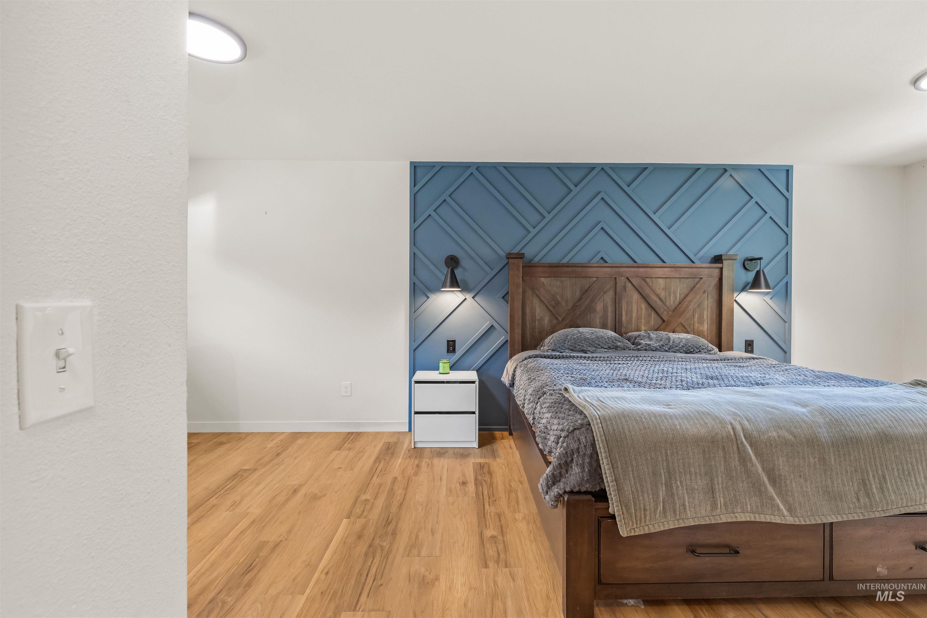 Wood-finish flooring throughout, complemented by a blue accent wall with geometric paneling