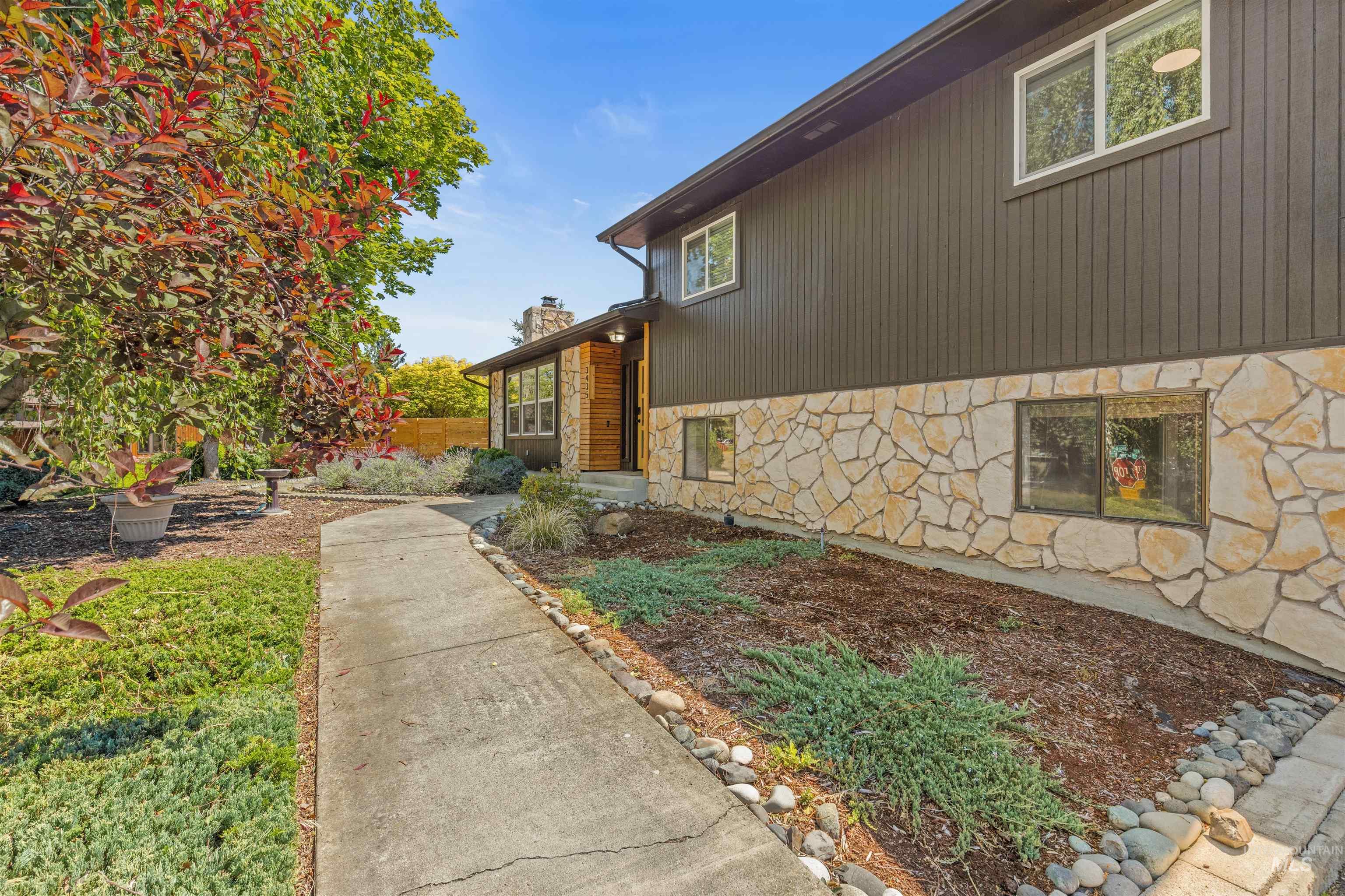 Exterior featuring stone veneer and vertical panel siding
