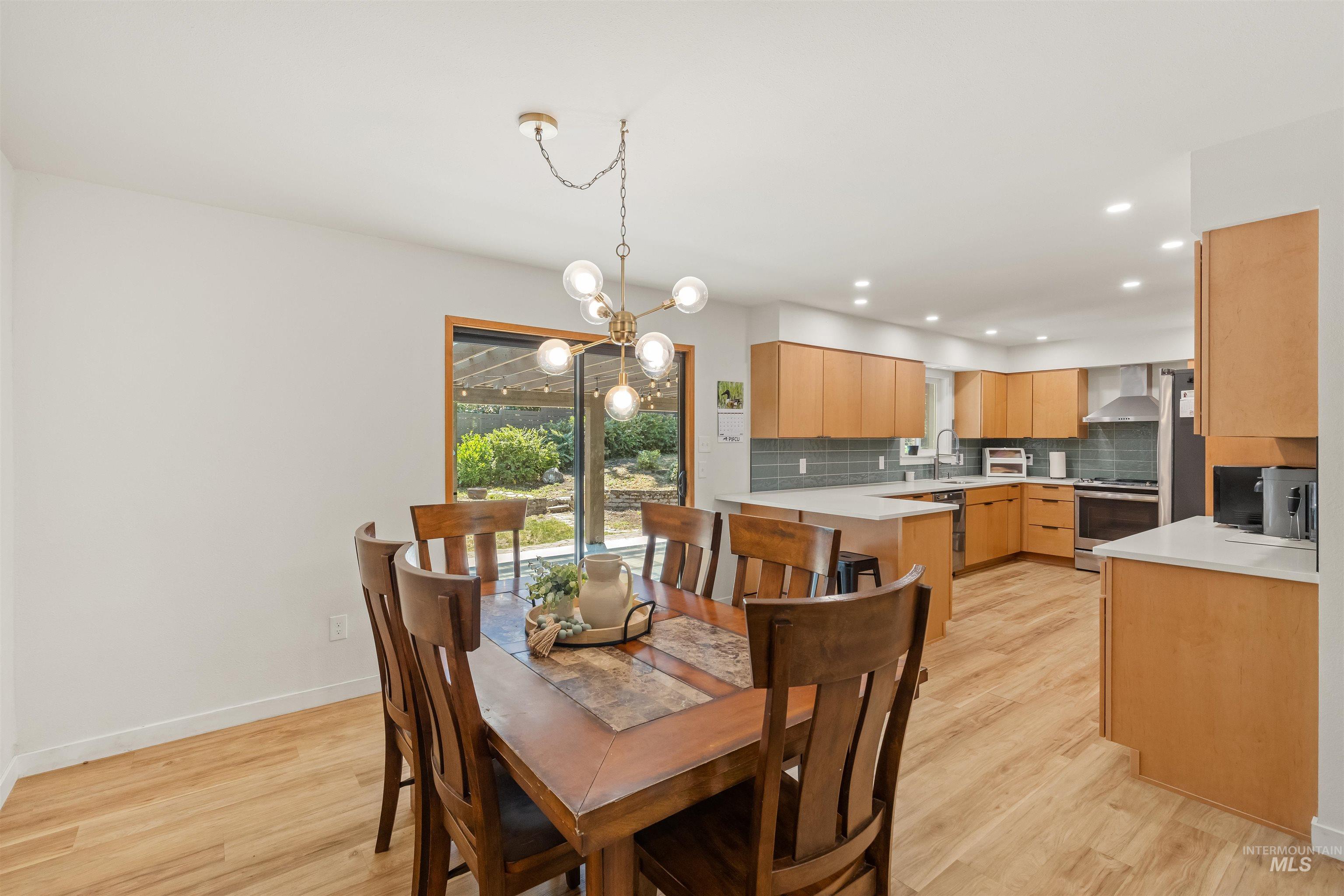 Open-concept living space featuring wood-finish flooring, a contemporary chandelier, and sliding glass doors opening to the exterior