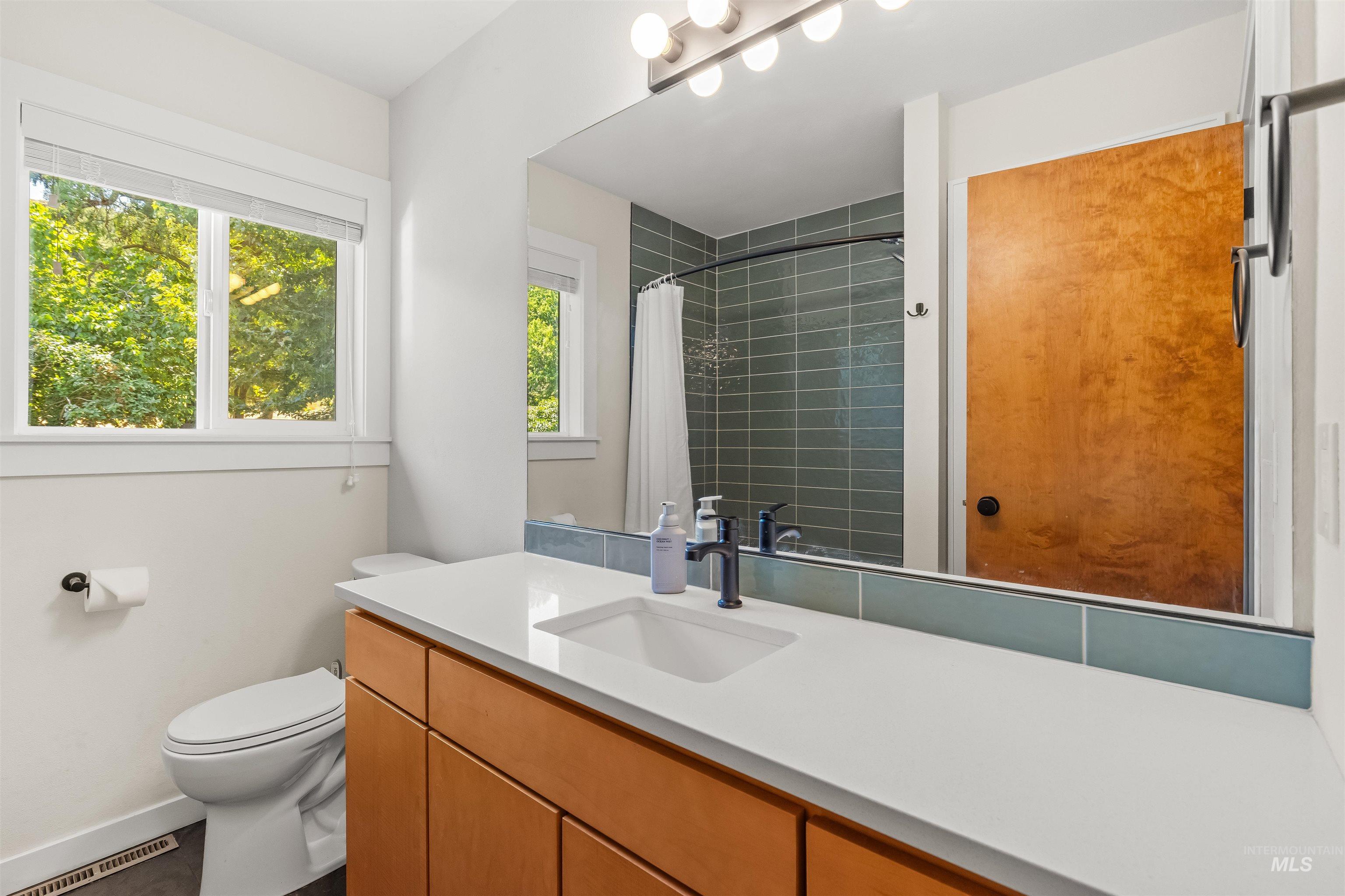 Modern bathroom featuring a single vanity with a white countertop, undermount sink, and matte black faucet