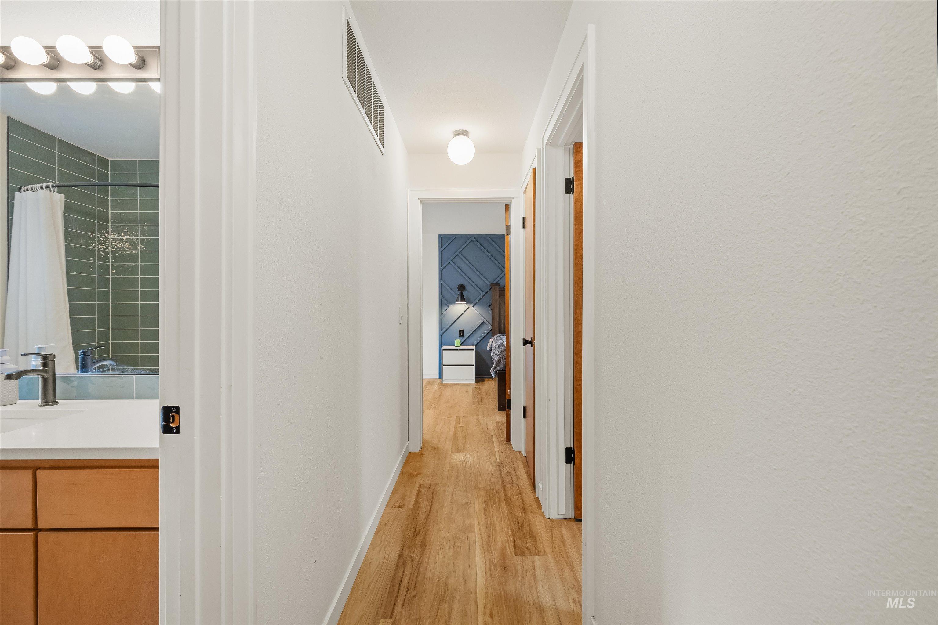 Hallway featuring wood-finish flooring, white walls, and recessed lighting