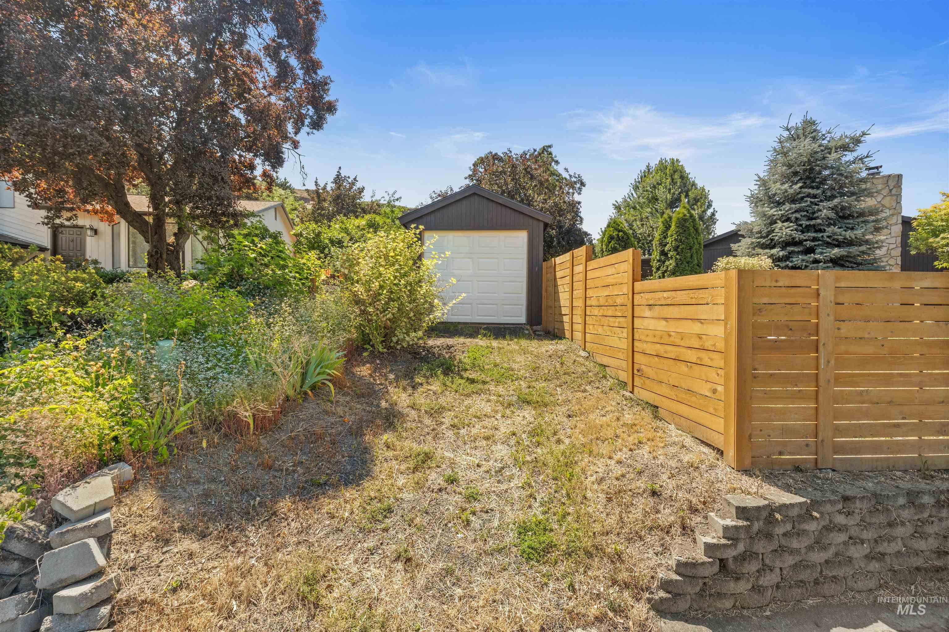 Detached garage with white overhead door, bordered by a newly installed horizontal wood fence