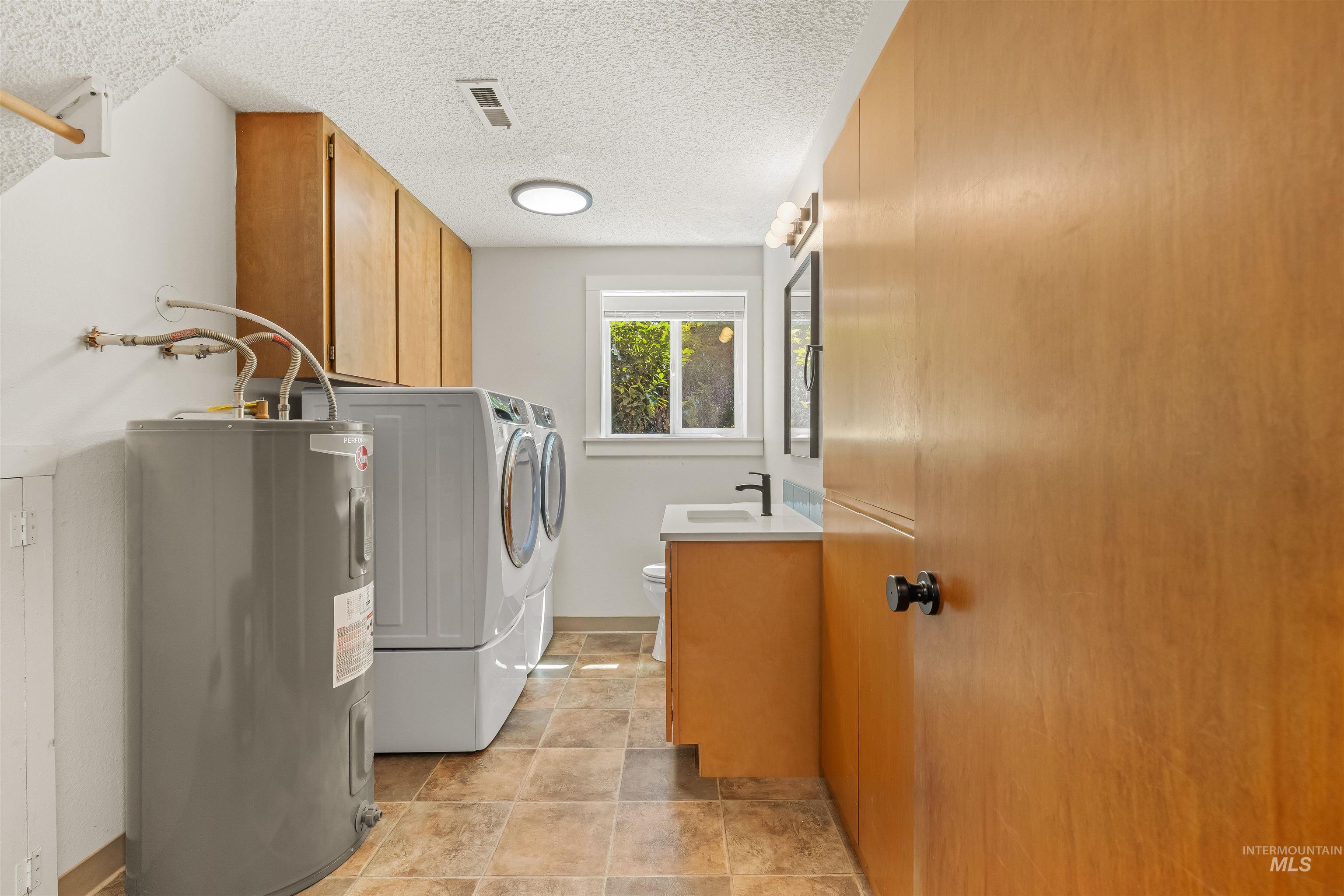 Dedicated laundry area featuring a water heater, stacked washer and dryer, and wood-finish cabinetry