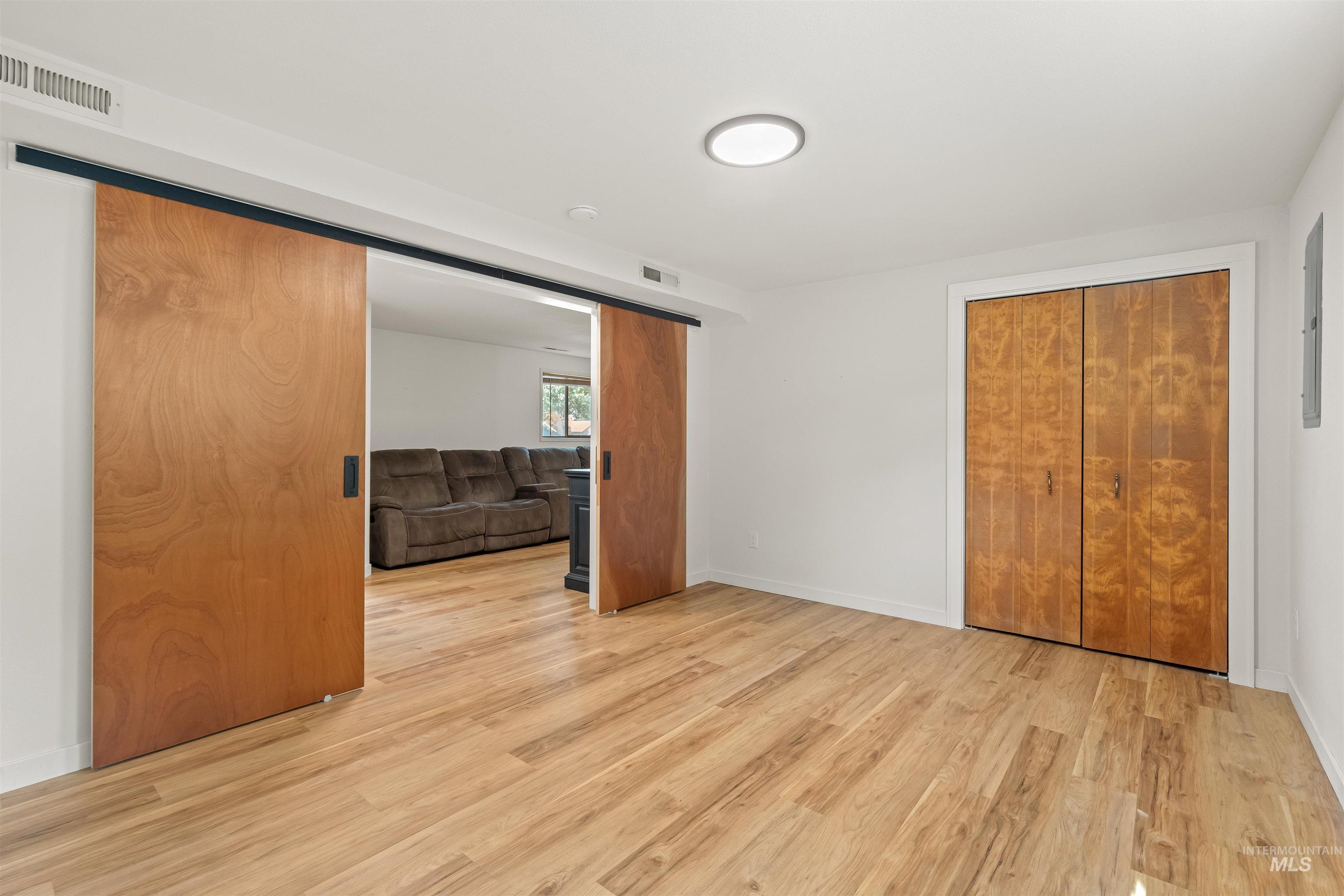 Room featuring wood-finish flooring, white walls, and a flush-mount ceiling light