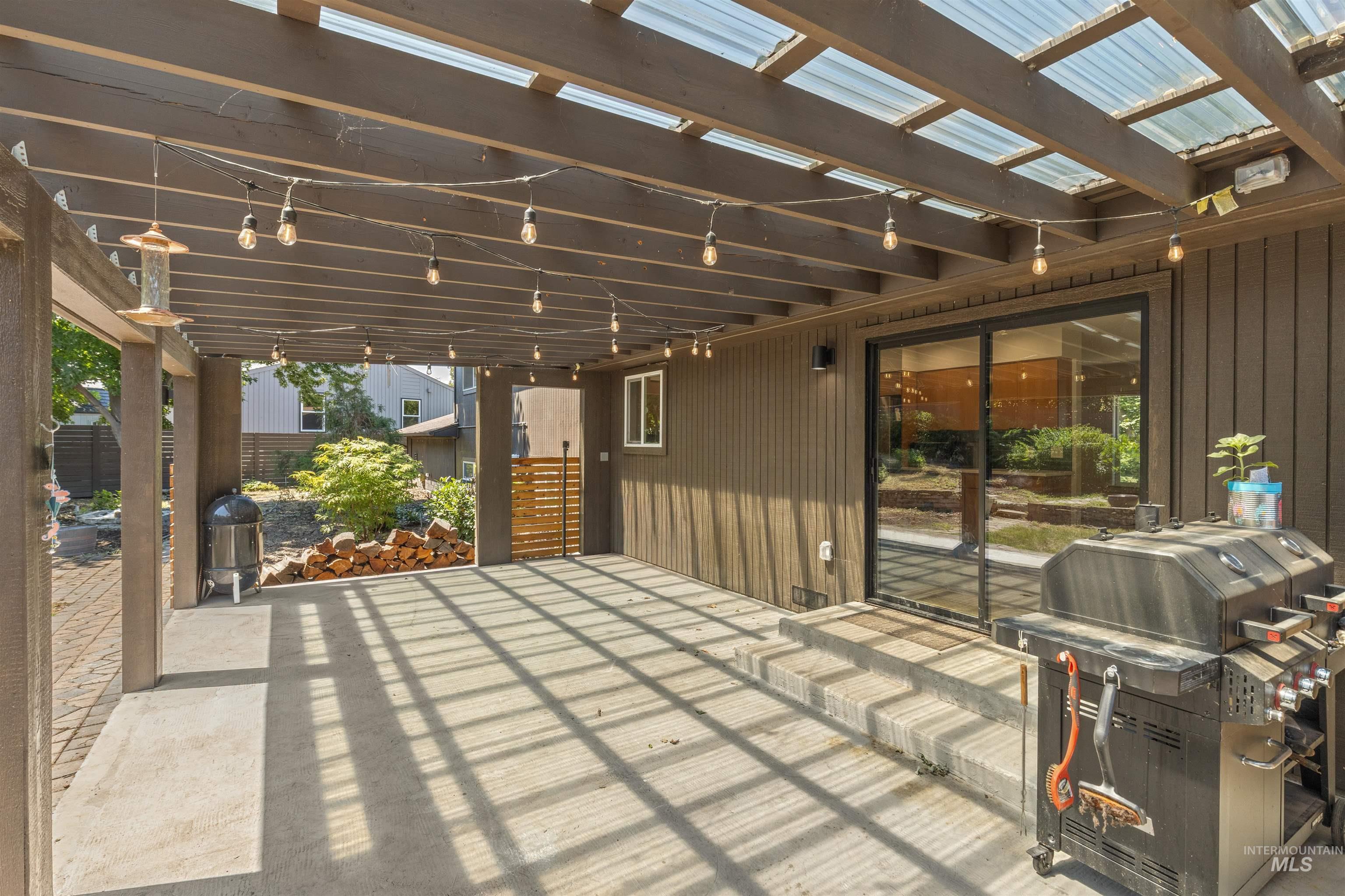 Covered patio featuring a translucent panel roof, string lighting, and a sliding glass door