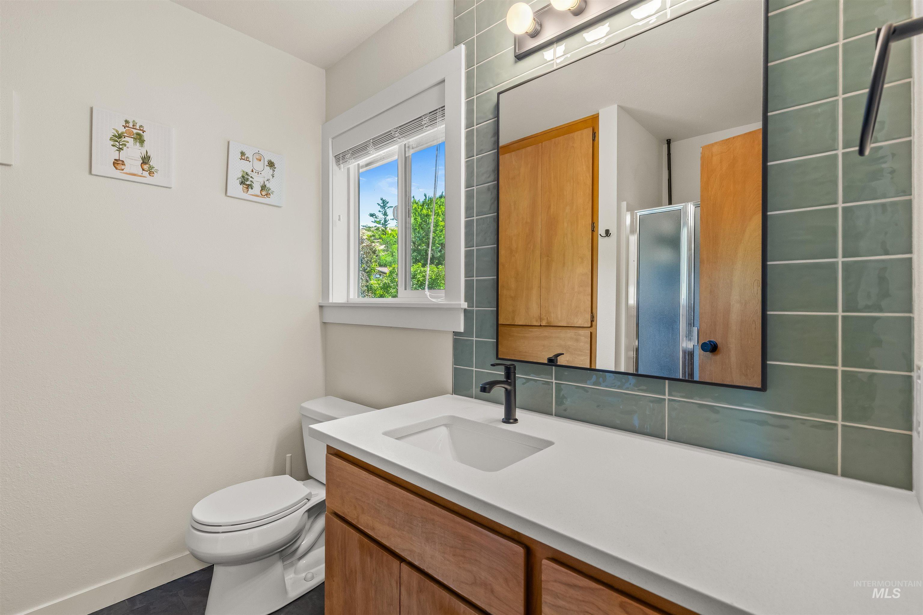 Bathroom featuring a wood-finish vanity with white countertop, integrated sink, and matte black faucet
