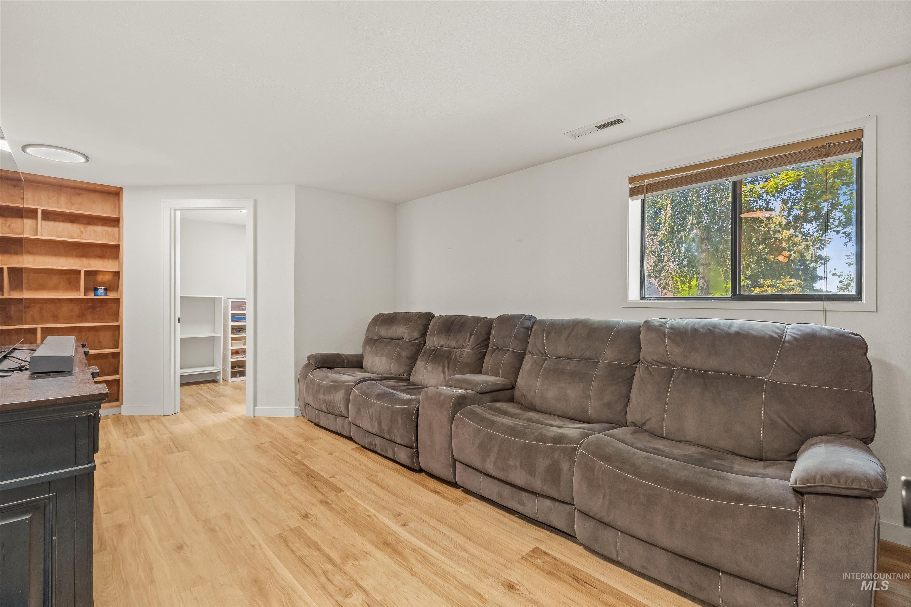 Bright room featuring wood-finish flooring, a built-in wood bookshelf, and a large window with natural light