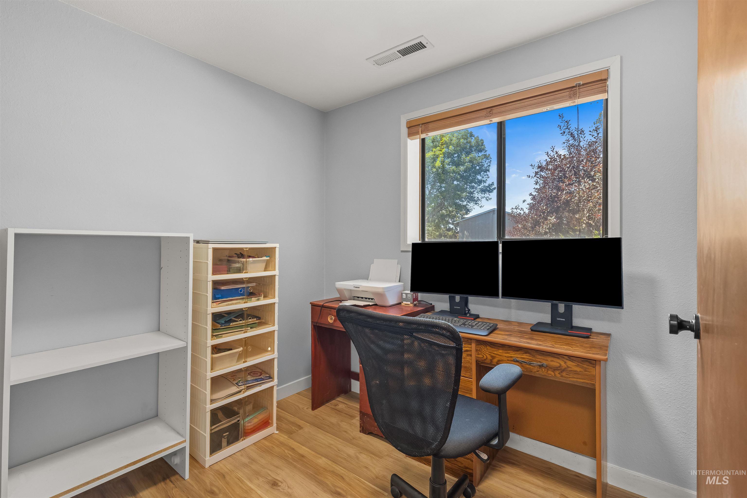 Room featuring light wood-finish flooring and a single window with blinds