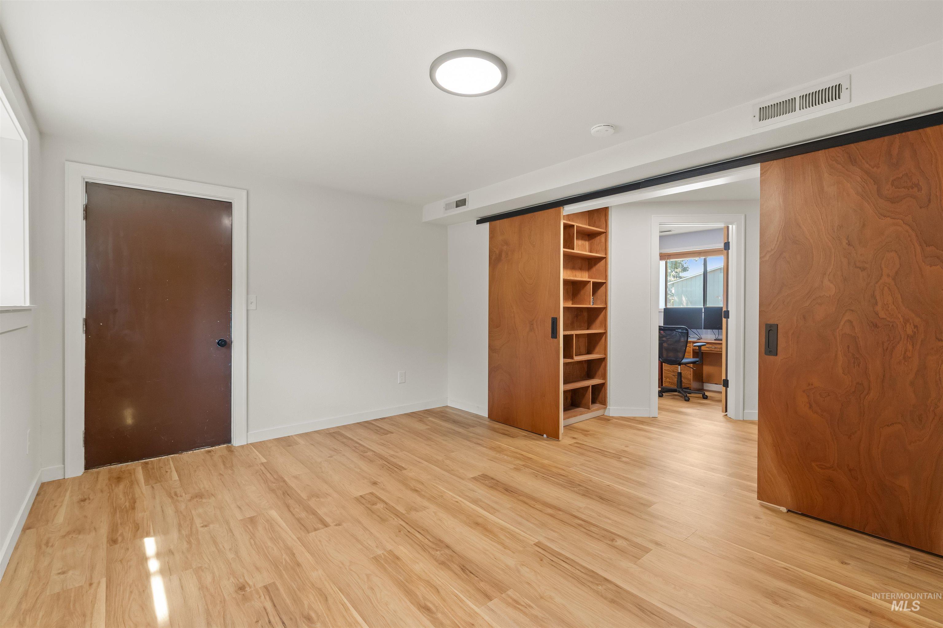 Spacious room featuring wood-finish flooring and white walls