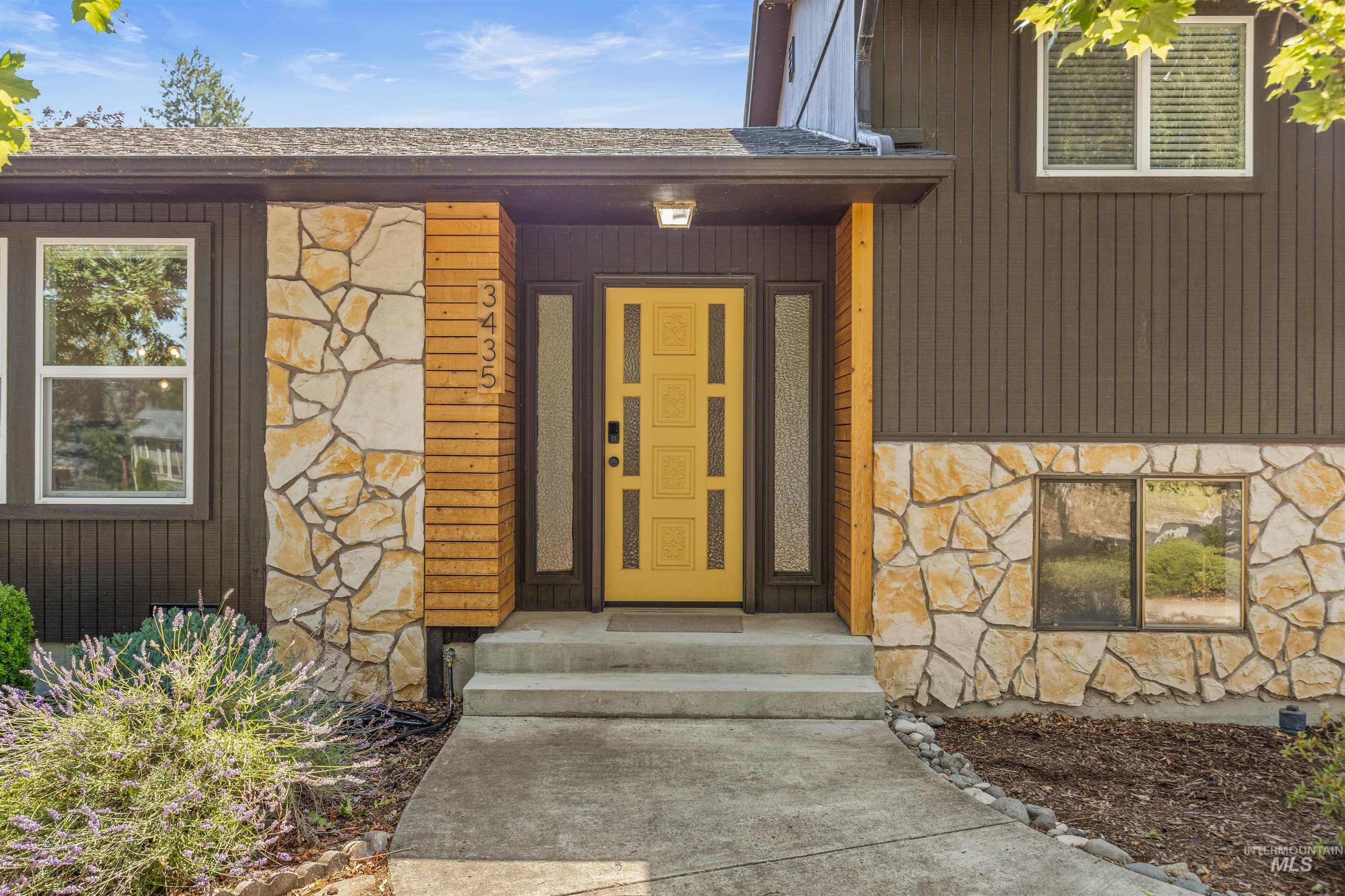 Entryway featuring a bright yellow door with decorative panels, flanked by frosted glass sidelights