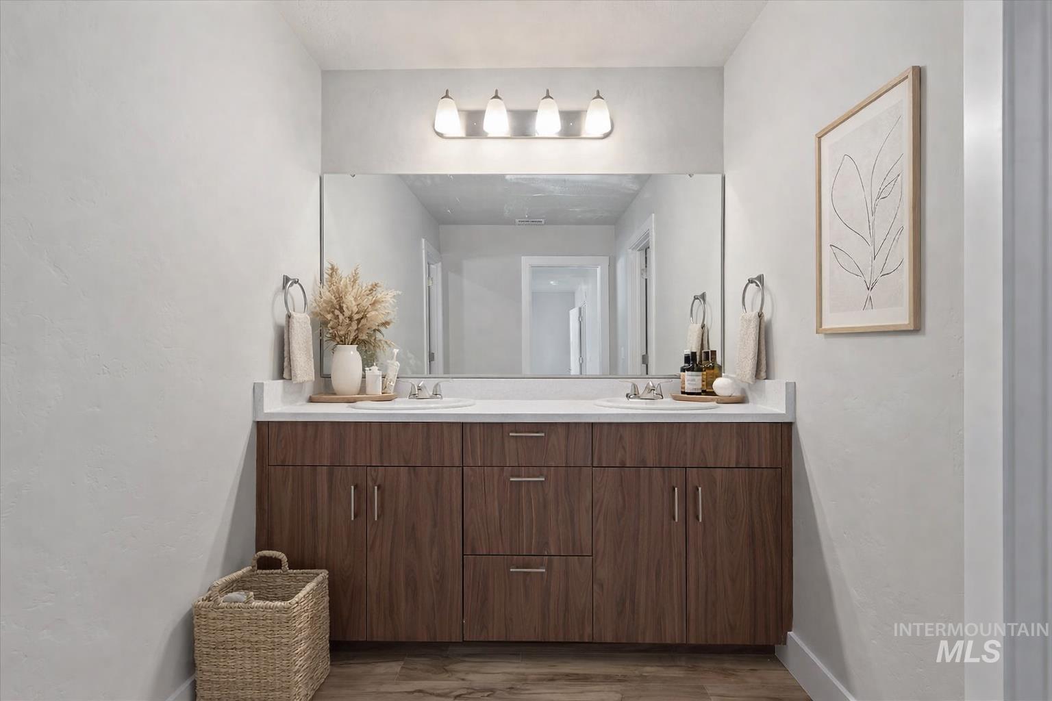 Full bathroom with double vanity, dark wood-style floors, and a textured wall
