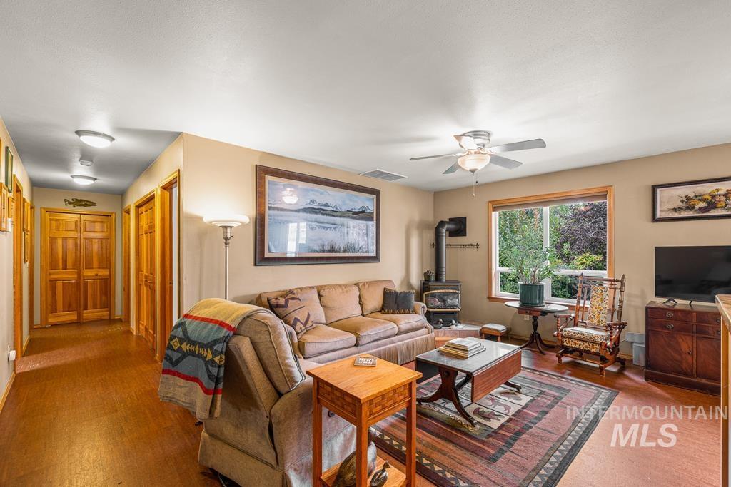Living area with a propane stove, cork floors, and a ceiling fan with hallway that leads to bedrooms.