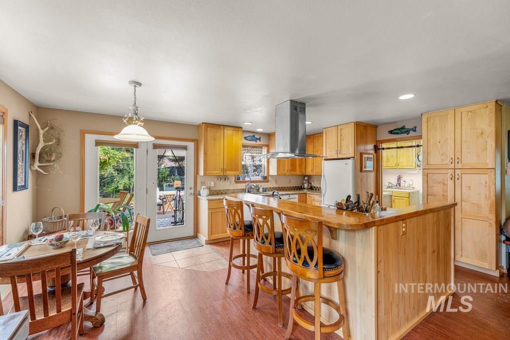 Kitchen with healthy amount of natural light, island exhaust hood, freestanding refrigerator, and recessed lighting