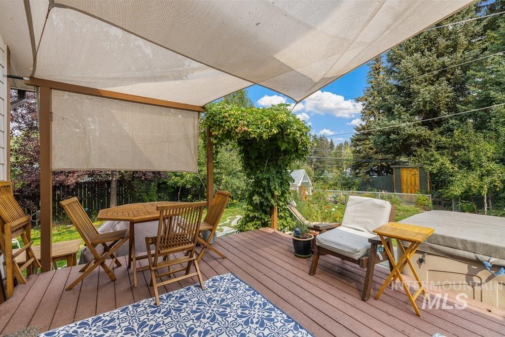 Wooden terrace featuring outdoor dining space, a fenced backyard, and a storage unit