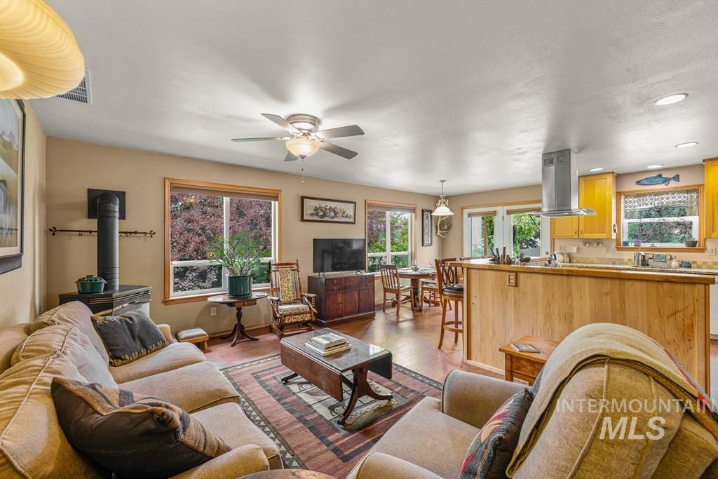 Living area with a wood stove, ceiling fan, and recessed lighting