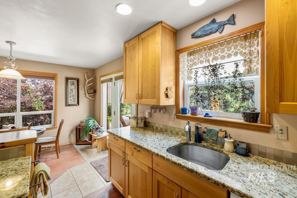 Kitchen with light stone counters, decorative light fixtures, and light tile patterned floors