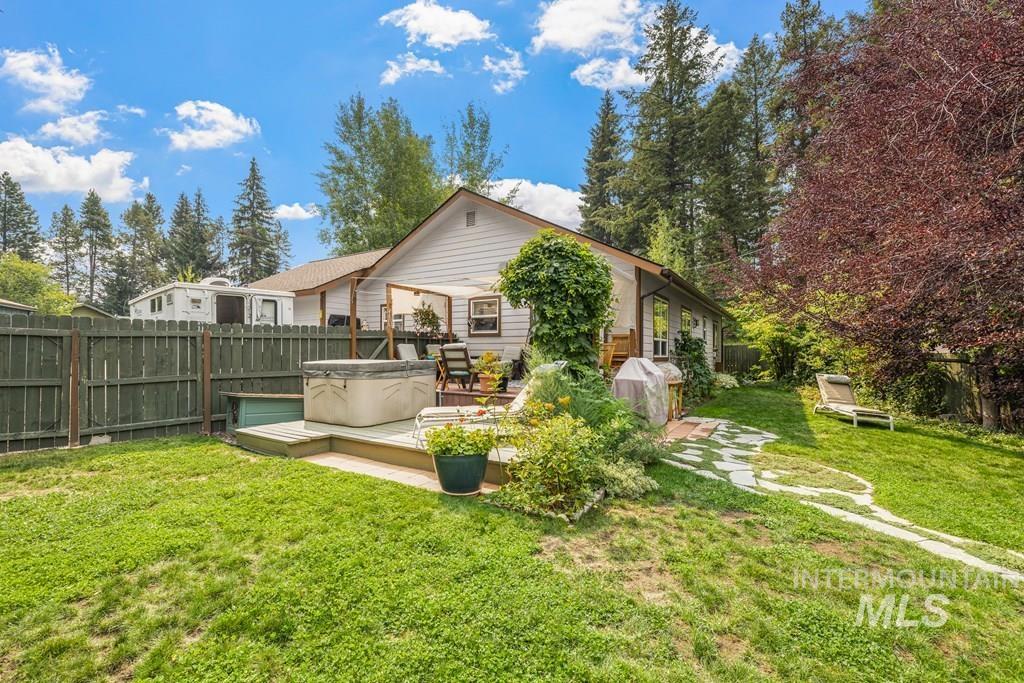 Back of house featuring a fenced backyard, a hot tub, and a deck. Looking at the back of the house from the vegetable garden.
