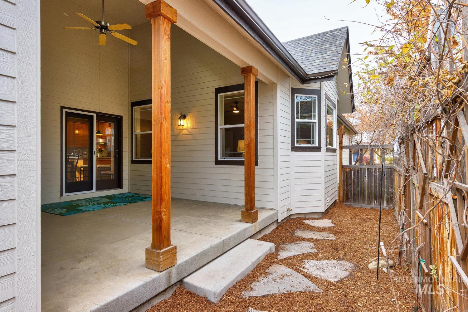 View of side of home featuring a ceiling fan, a shingled roof, and a patio area