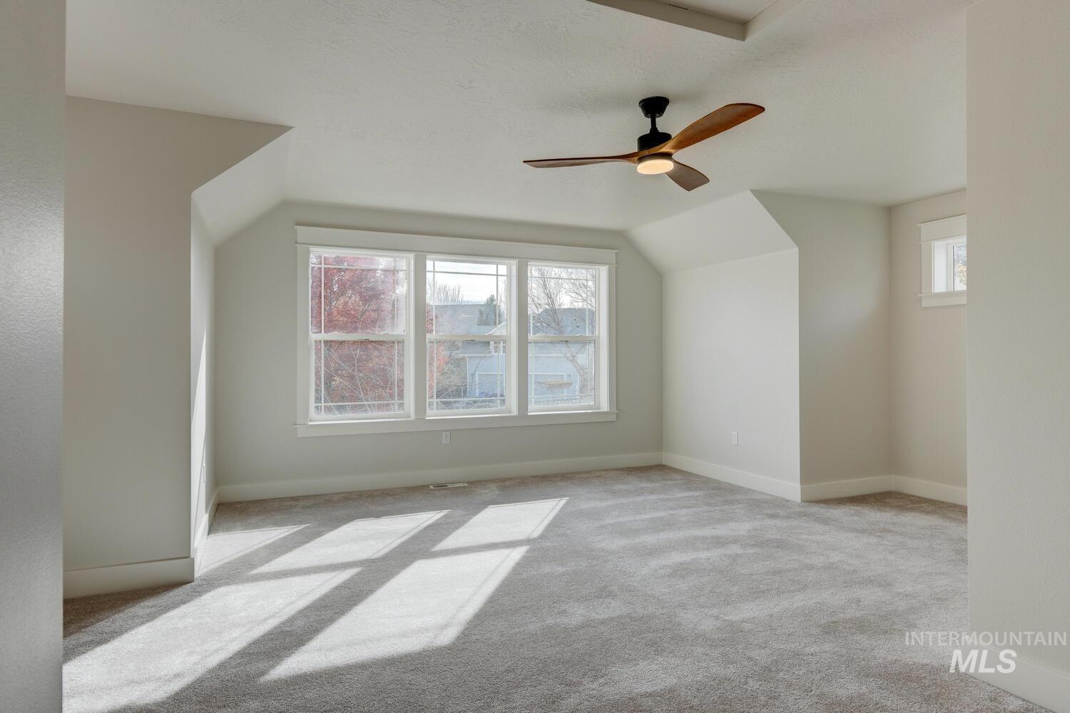 Additional living space featuring light colored carpet, lofted ceiling, and ceiling fan
