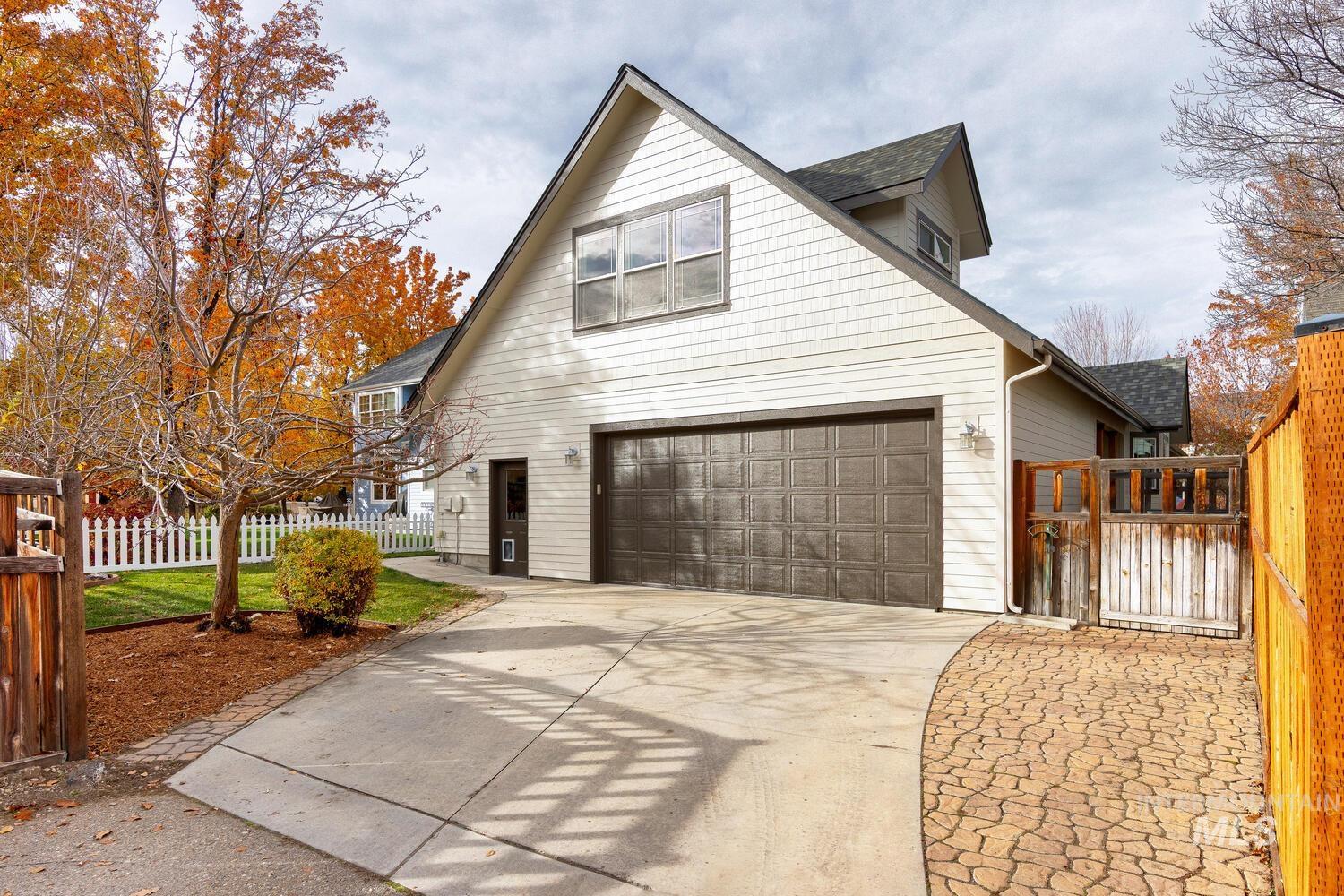 View of home's exterior with concrete driveway, a garage, a gate, and a shingled roof