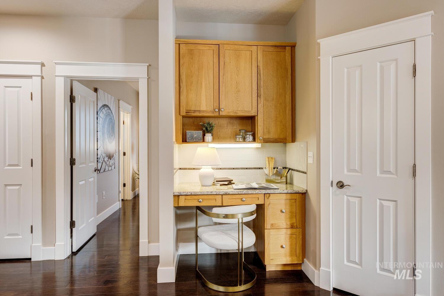 Kitchen with built in study area, backsplash, dark wood finished floors, open shelves, and brown cabinetry