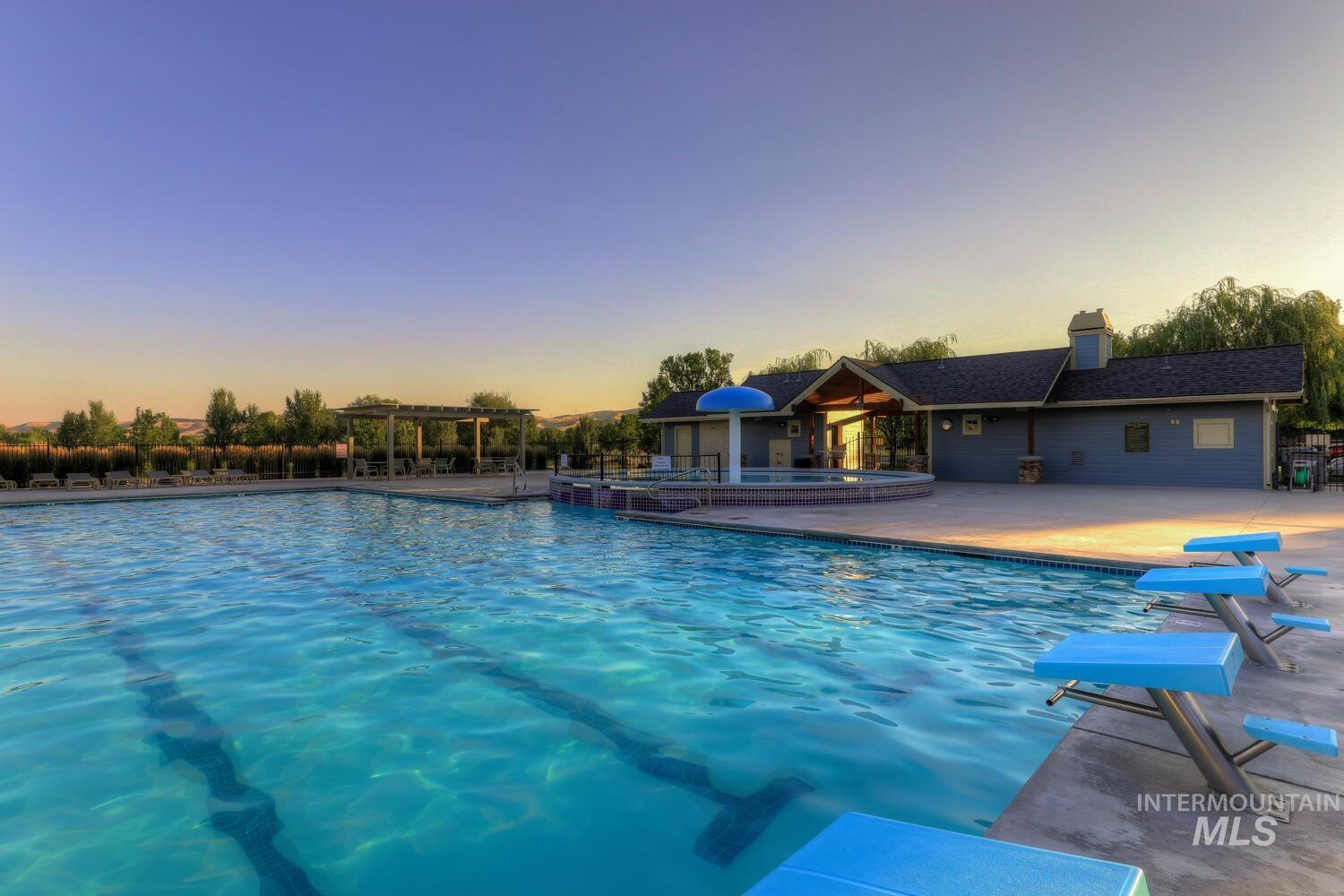 Pool at dusk featuring a community pool and a patio area