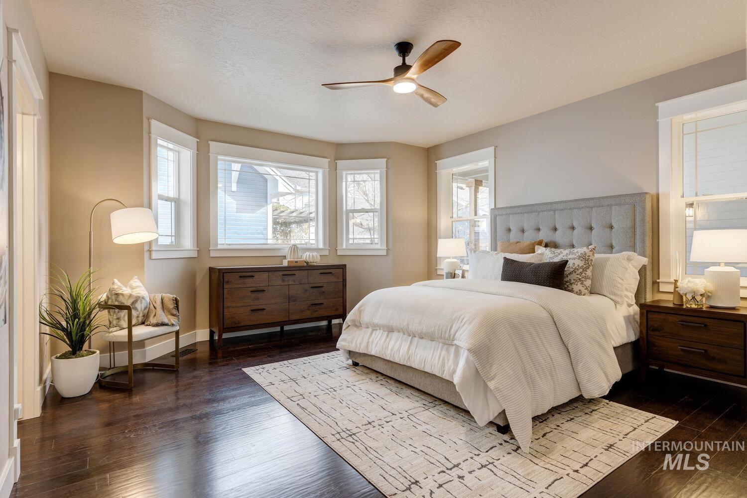Bedroom with dark wood-style flooring, a ceiling fan, and a textured ceiling