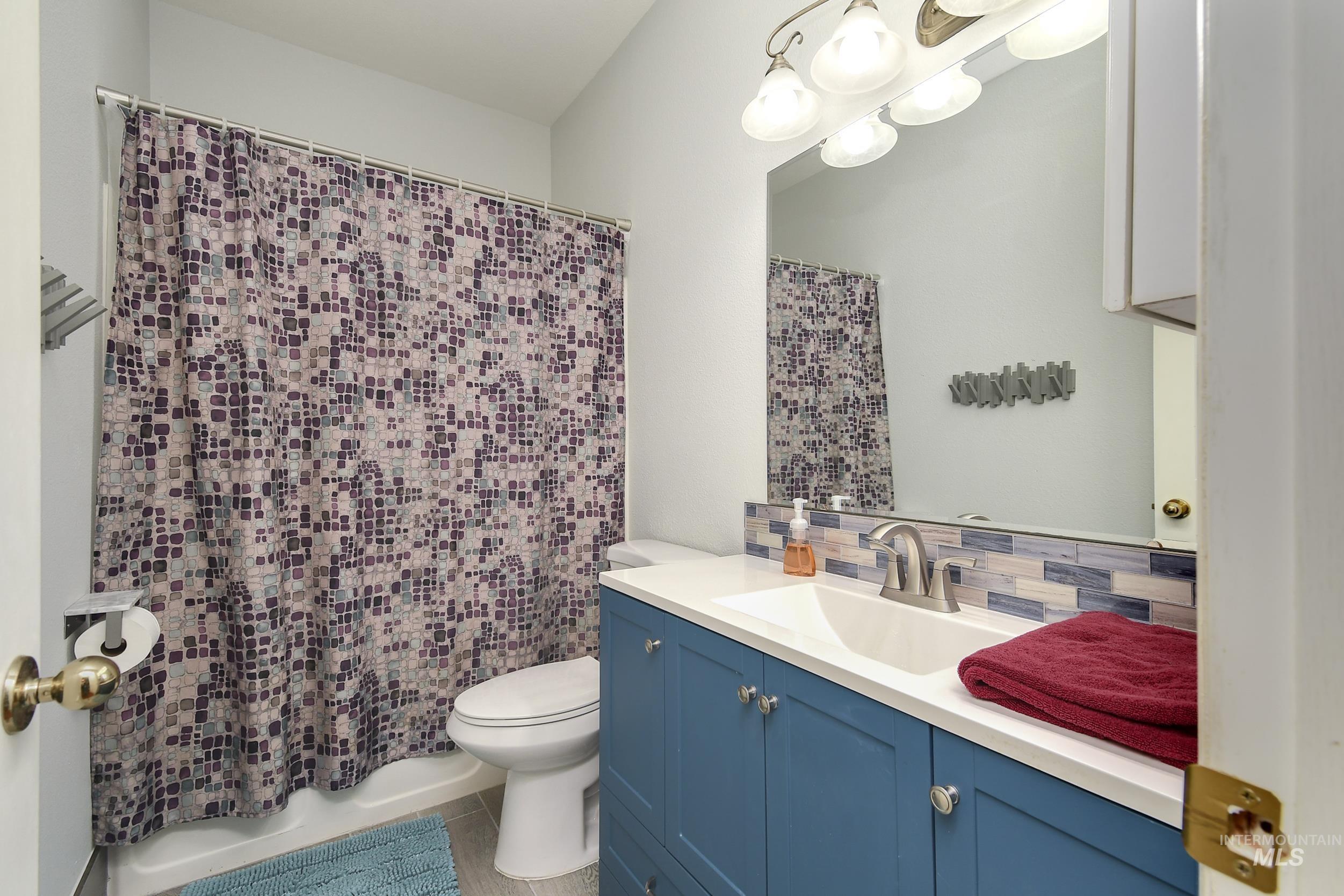 Bathroom with a shower with curtain, vanity, and tasteful backsplash