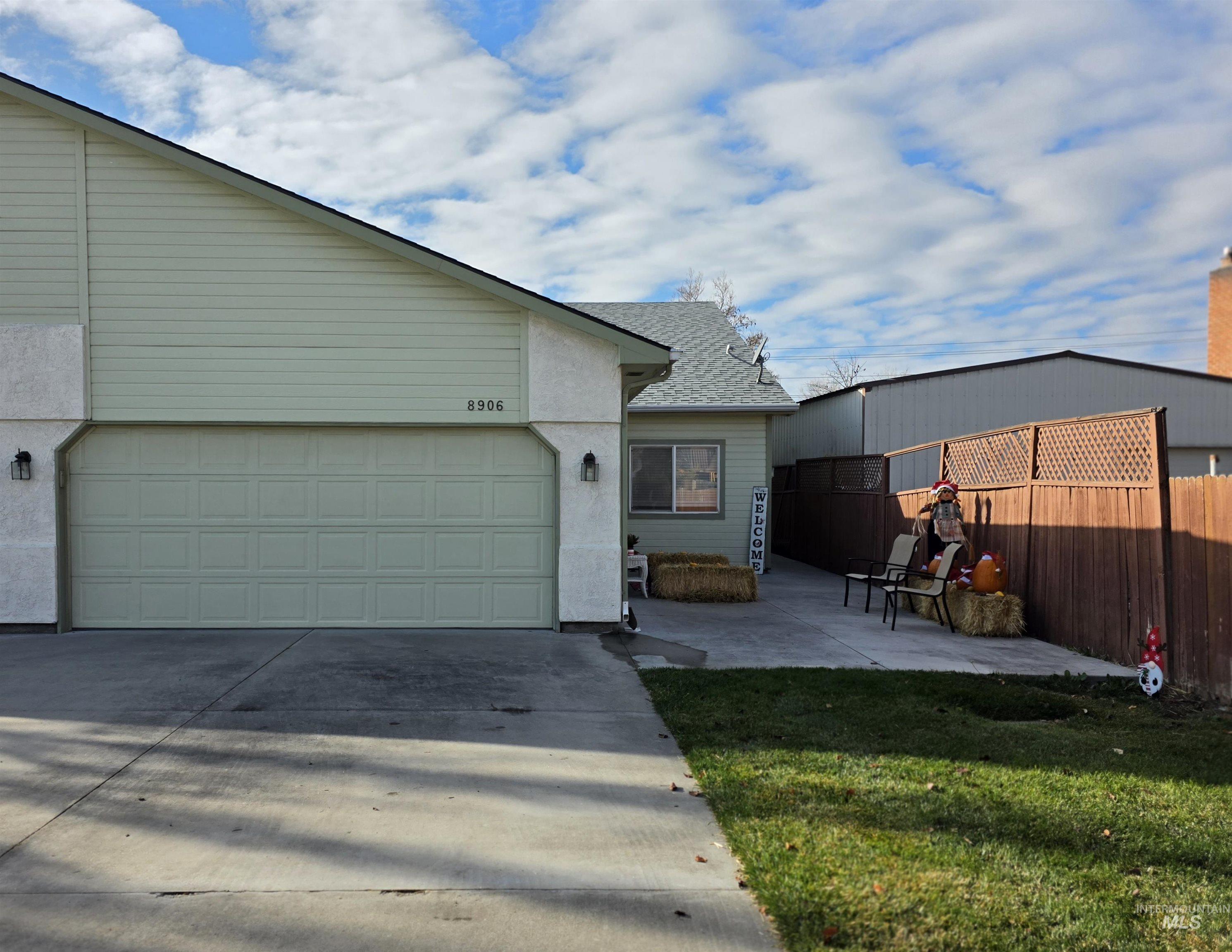 View of front of home with concrete driveway, a patio, roof with shingles, and an attached garage