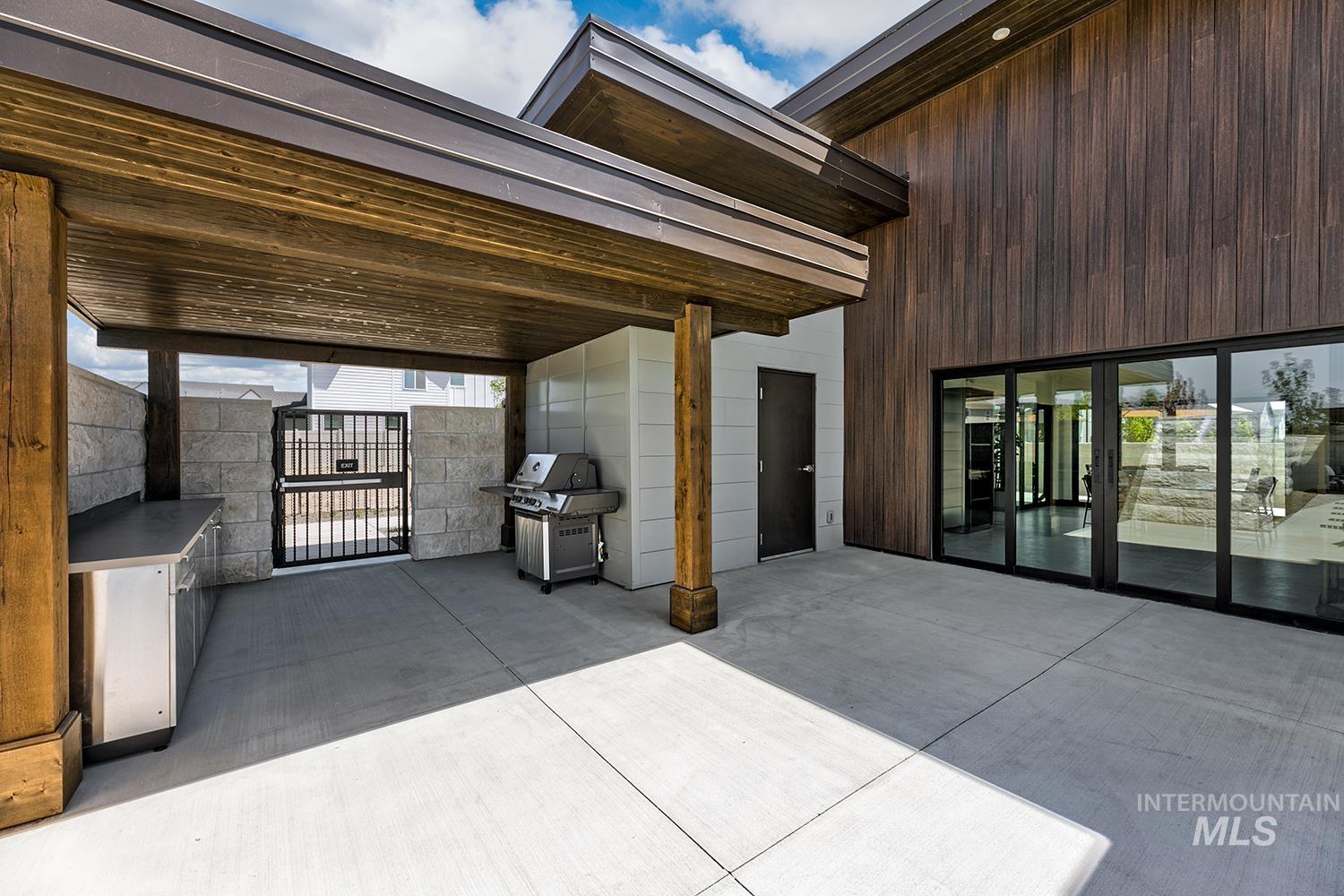View of patio with a grill and a gate