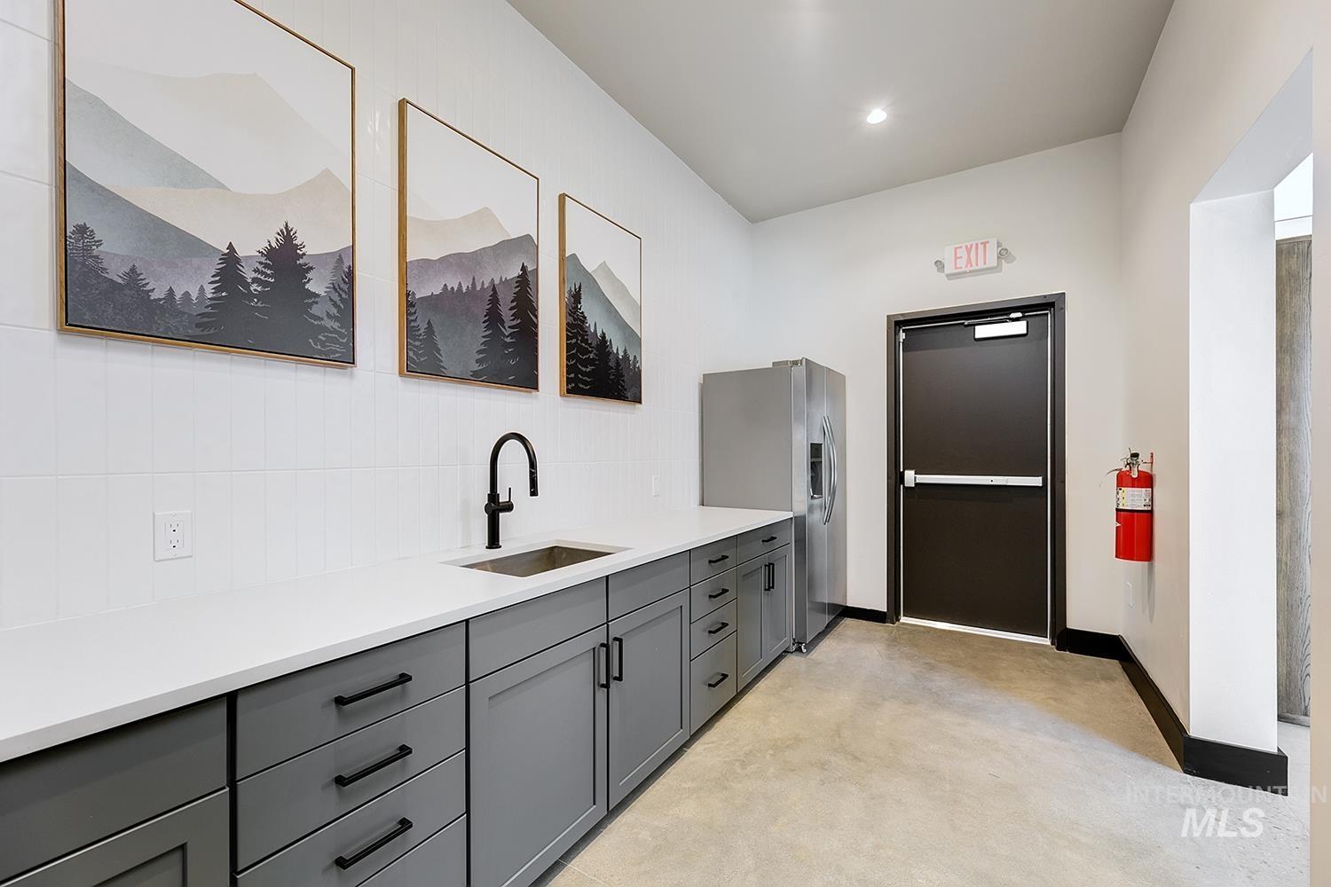 Kitchen featuring stainless steel fridge, gray cabinets, tasteful backsplash, and light countertops