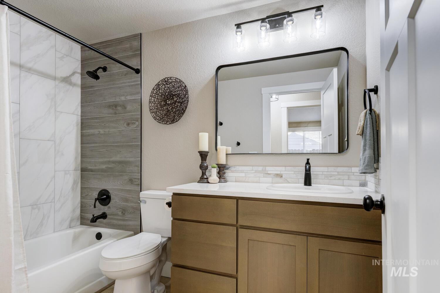 Bathroom featuring shower / tub combo, vanity, and a textured wall