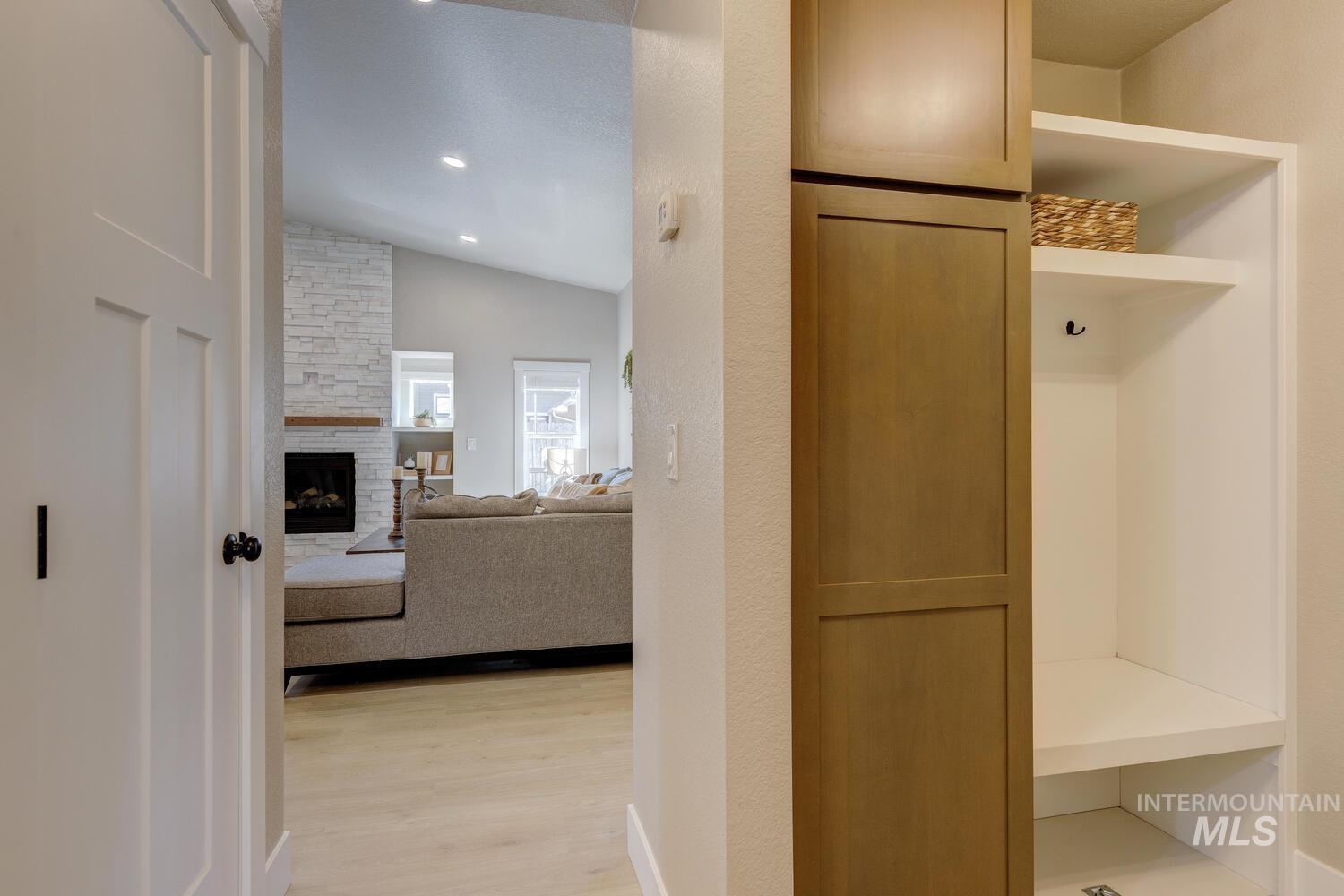 Mudroom featuring vaulted ceiling, light wood finished floors, a fireplace, and recessed lighting