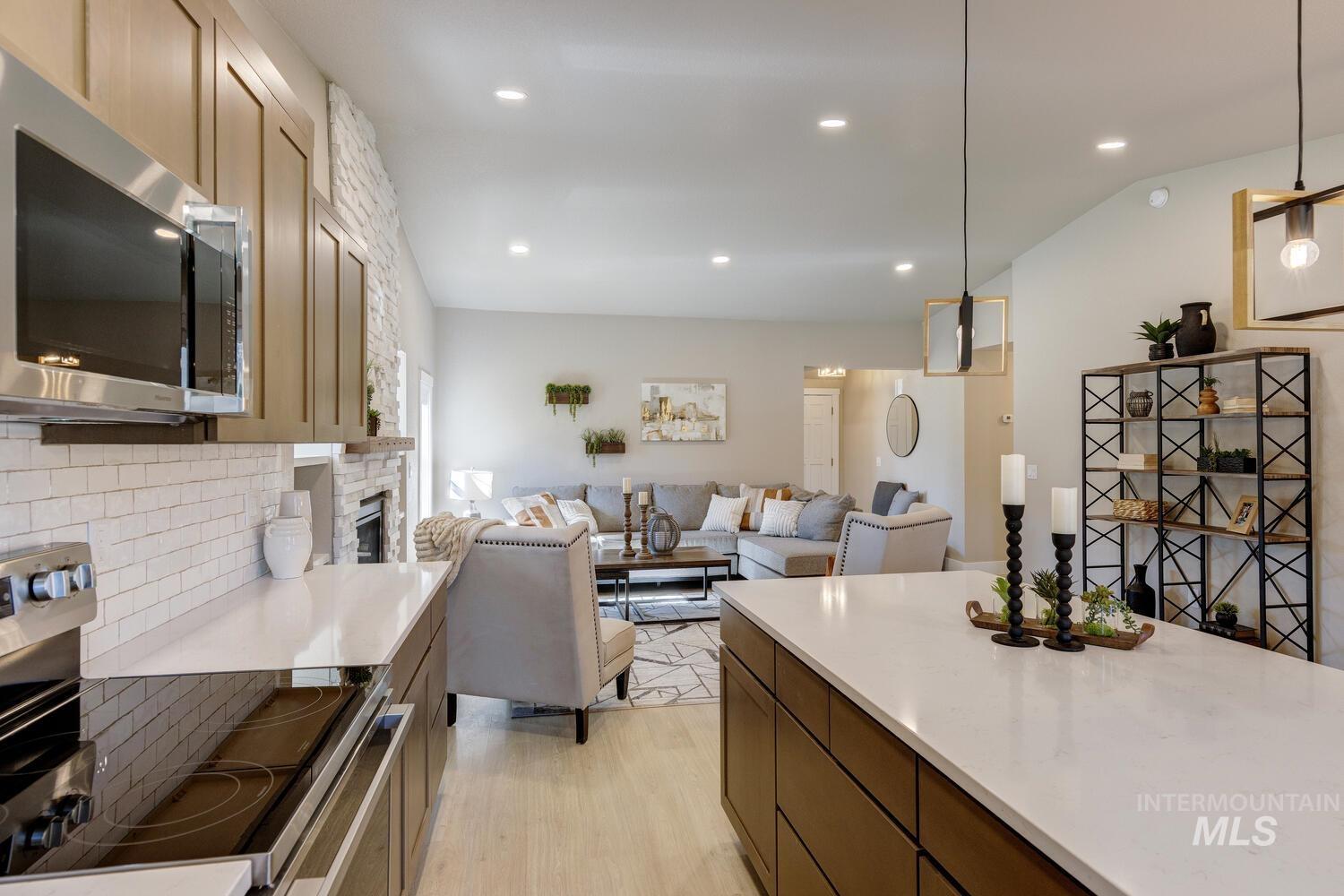 Kitchen featuring appliances with stainless steel finishes, pendant lighting, recessed lighting, backsplash, and open floor plan