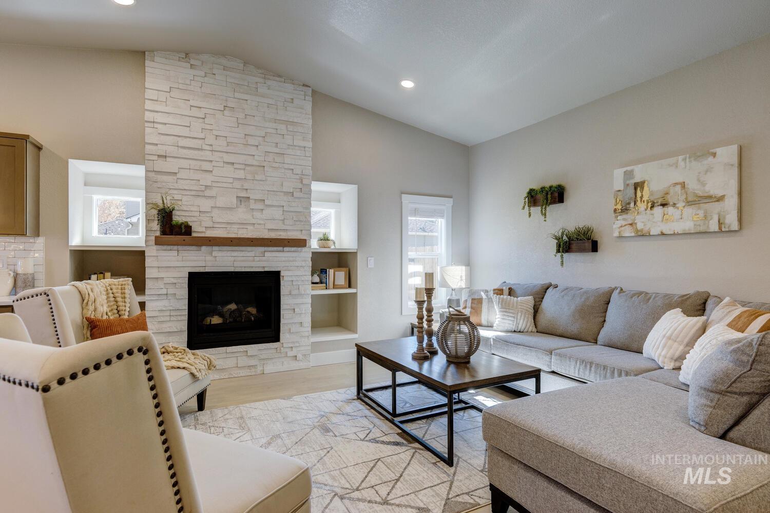 Living room featuring plenty of natural light, vaulted ceiling, a fireplace, light wood-style flooring, and recessed lighting