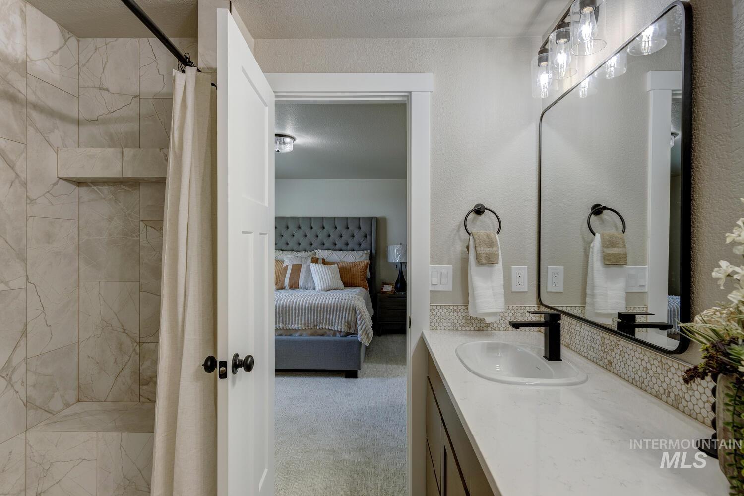 Full bath featuring vanity, connected bathroom, tiled shower, and light colored carpet