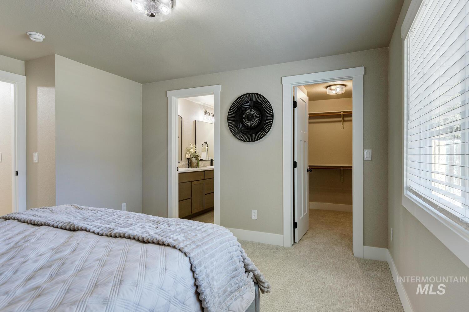 Bedroom featuring light colored carpet and a walk in closet