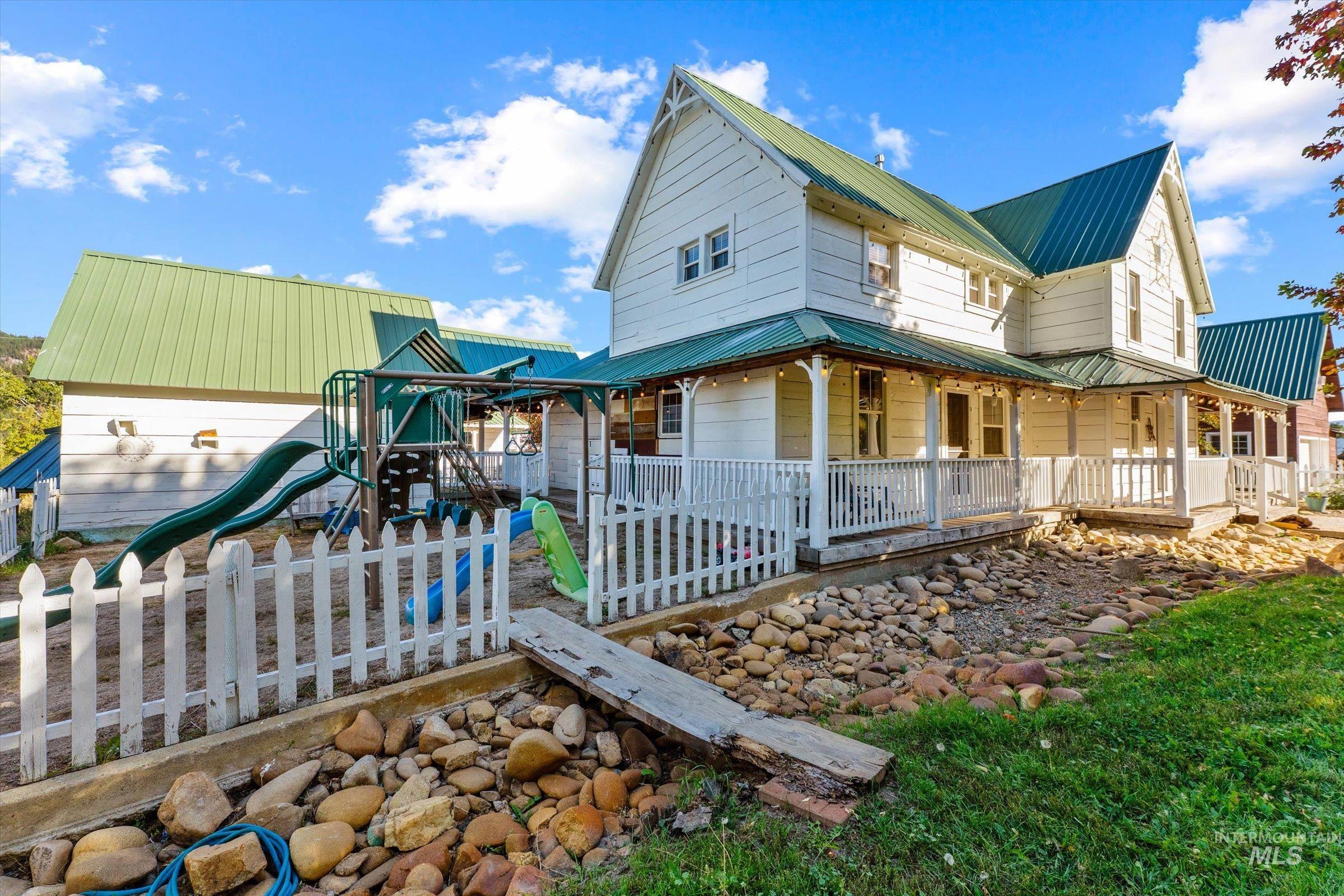 View of home's exterior featuring a metal roof, covered porch, and a playground
