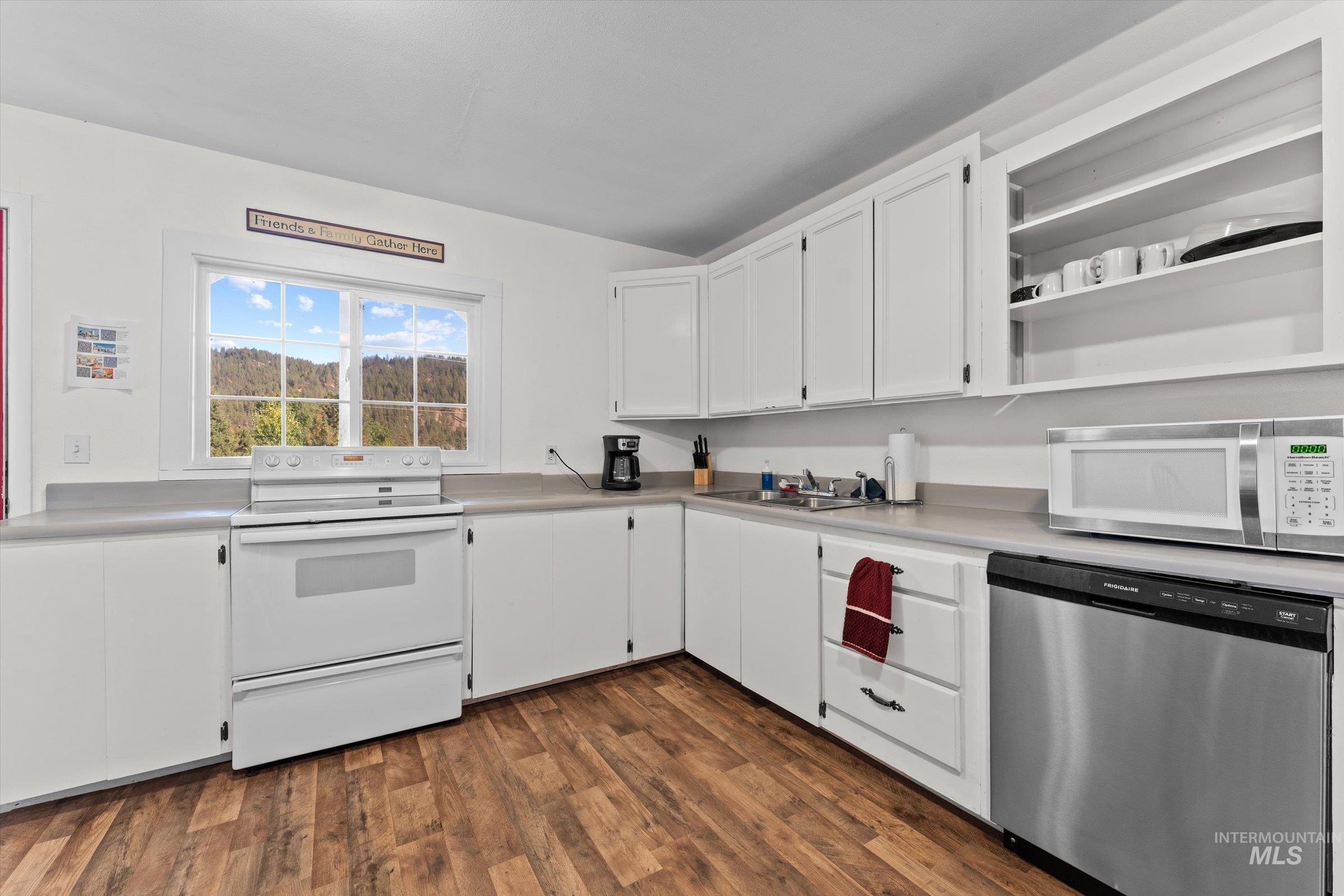 Kitchen featuring stainless steel dishwasher, white cabinetry, white electric stove, light countertops, and dark wood-type flooring
