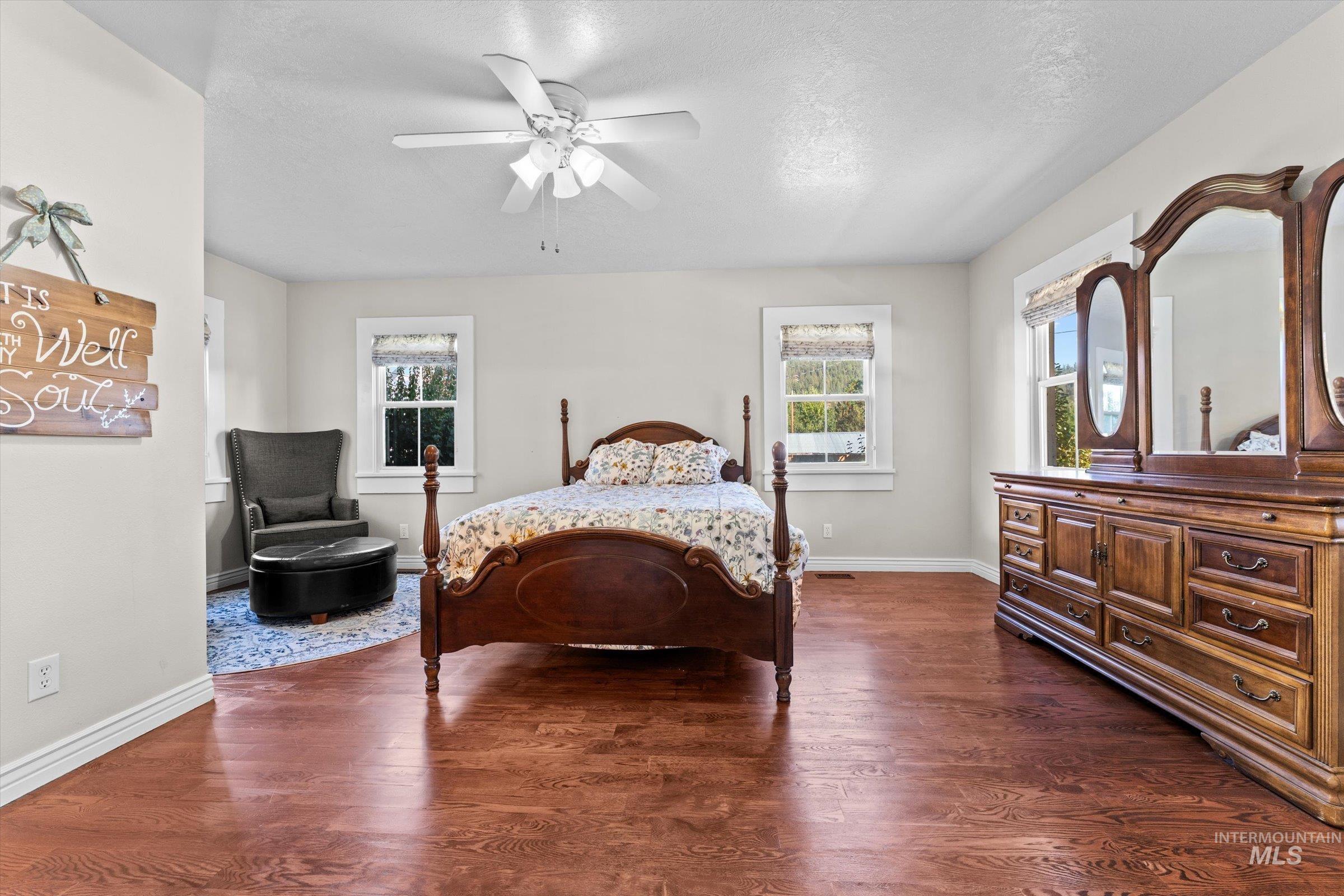 Bedroom featuring dark wood-type flooring, a ceiling fan, and a textured ceiling