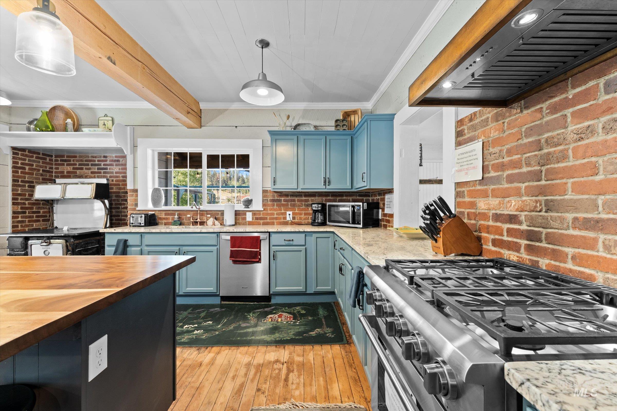 Kitchen with ornamental molding, exhaust hood, light wood-style flooring, wooden counters, and stainless steel appliances