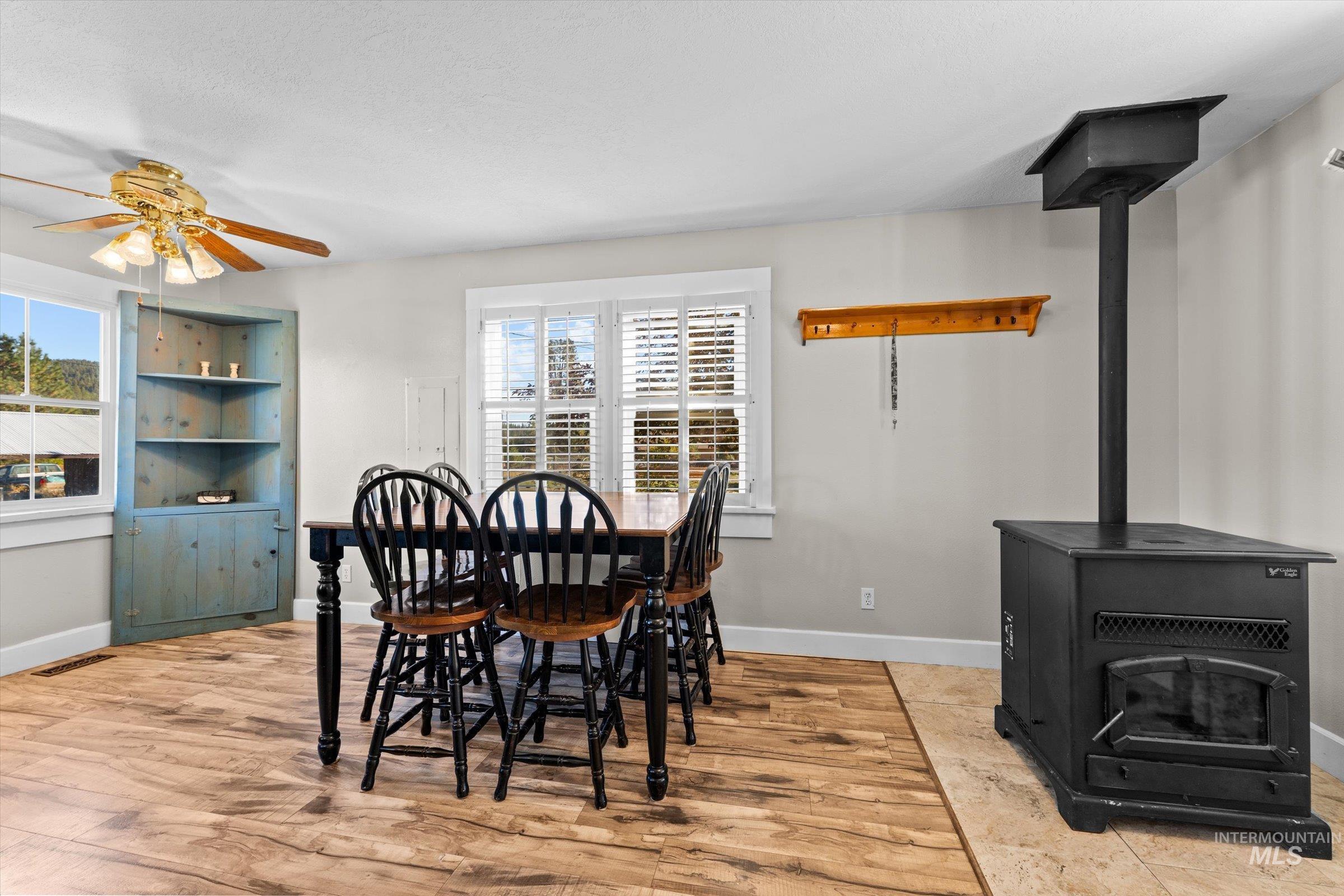 Dining room featuring a wood stove, light wood-style flooring, and ceiling fan
