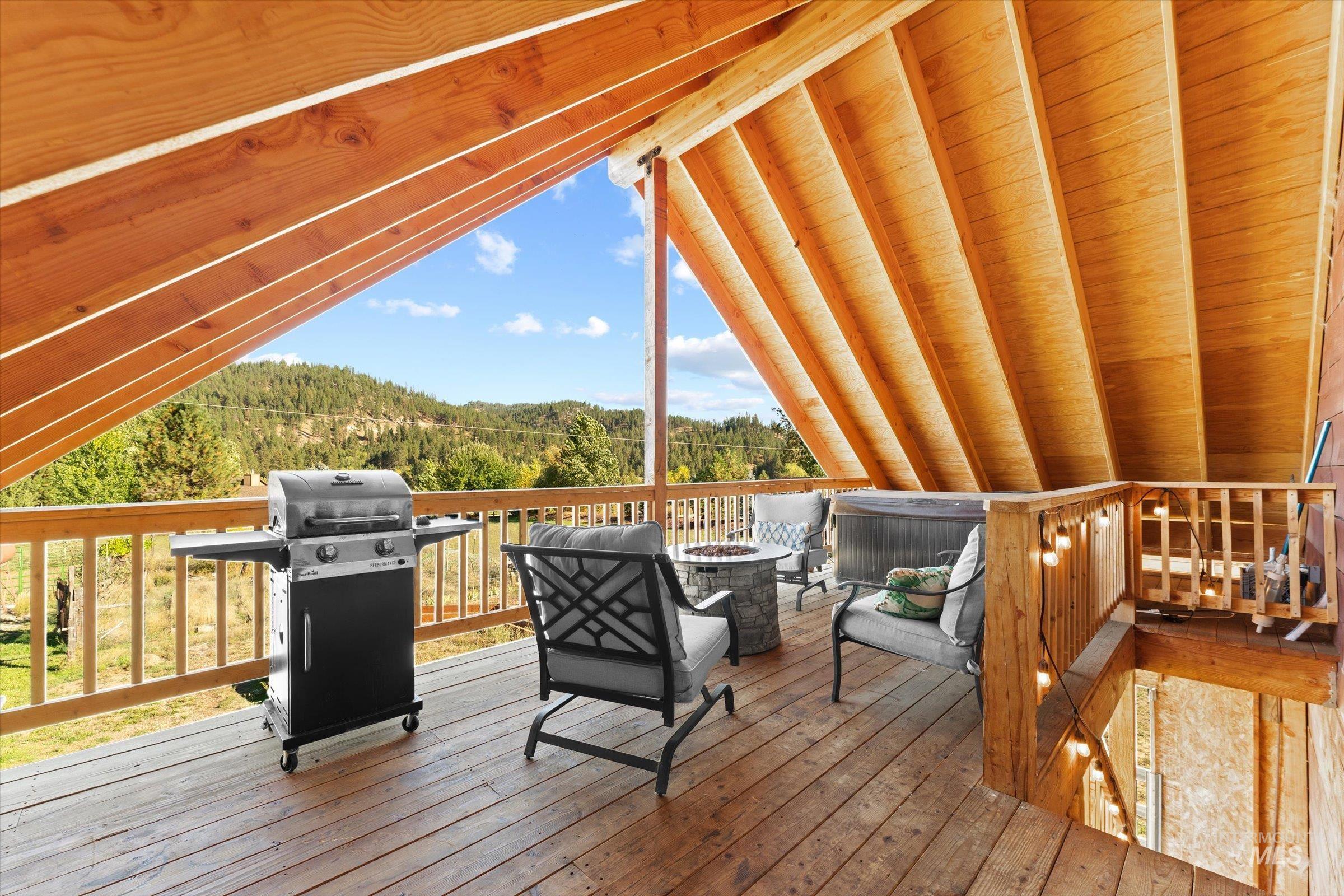 Deck featuring a wooded view, an outdoor fire pit, and a grill