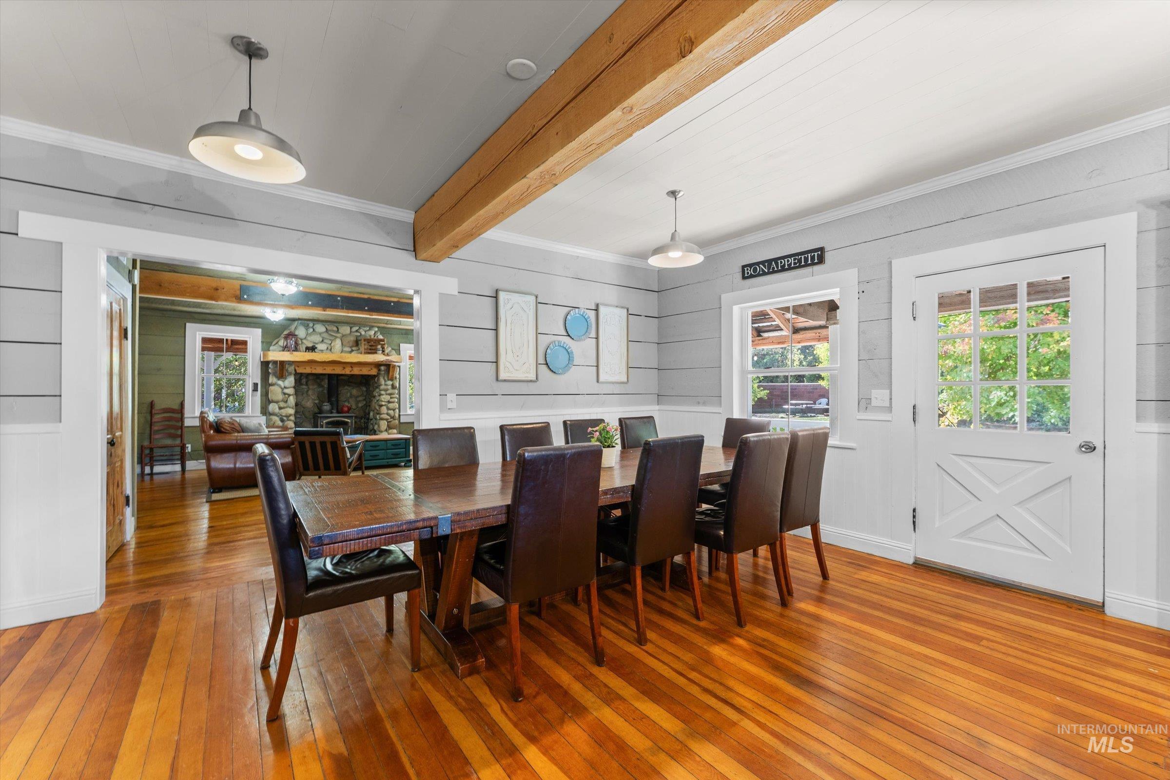 Dining area featuring light wood-style floors, crown molding, beam ceiling, plenty of natural light, and a fireplace
